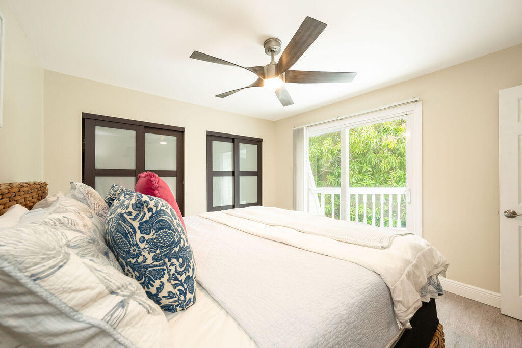 Bedroom with a white bed, dark-framed closet doors, and a window overlooking greenery.