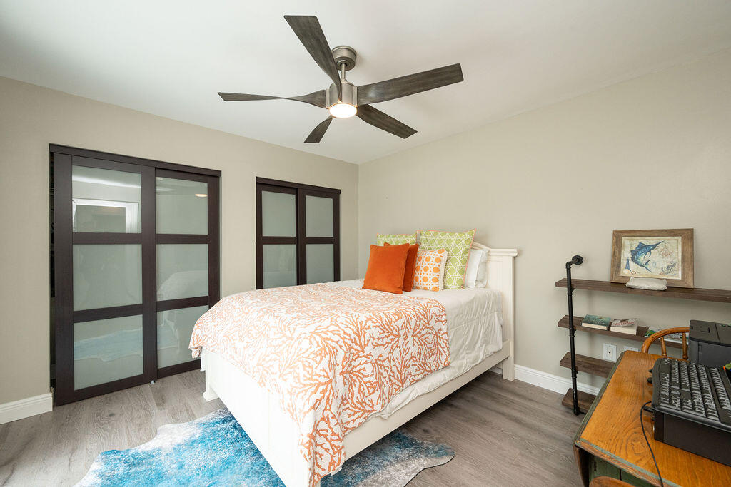 Bedroom with a coral-patterned bedspread, dark-framed sliding doors, and a wooden desk.