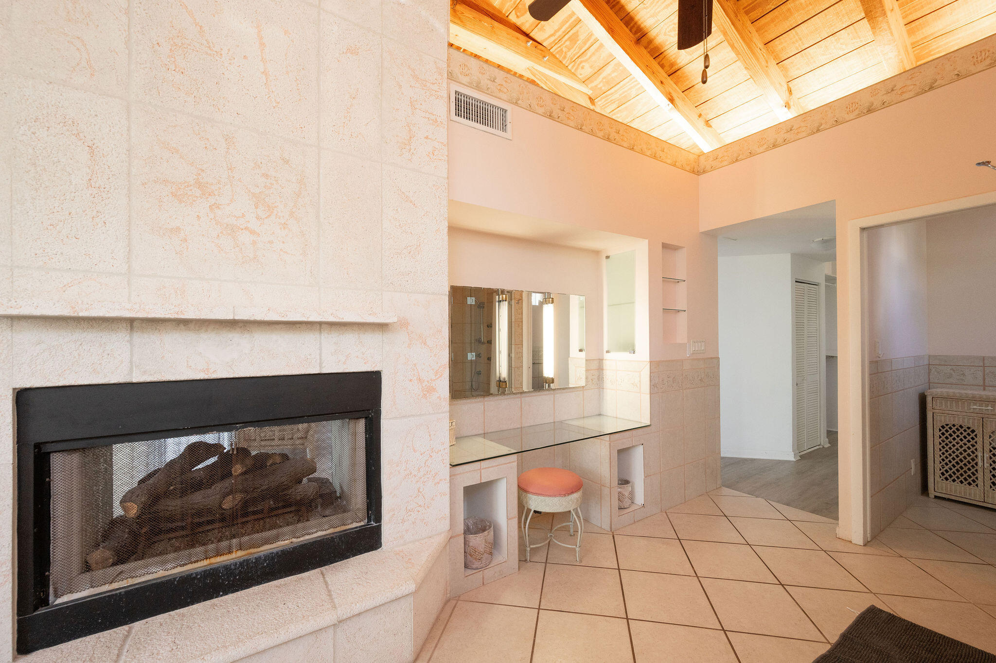 Bathroom with a stone fireplace, tiled vanity, and vaulted wood-beam ceiling.