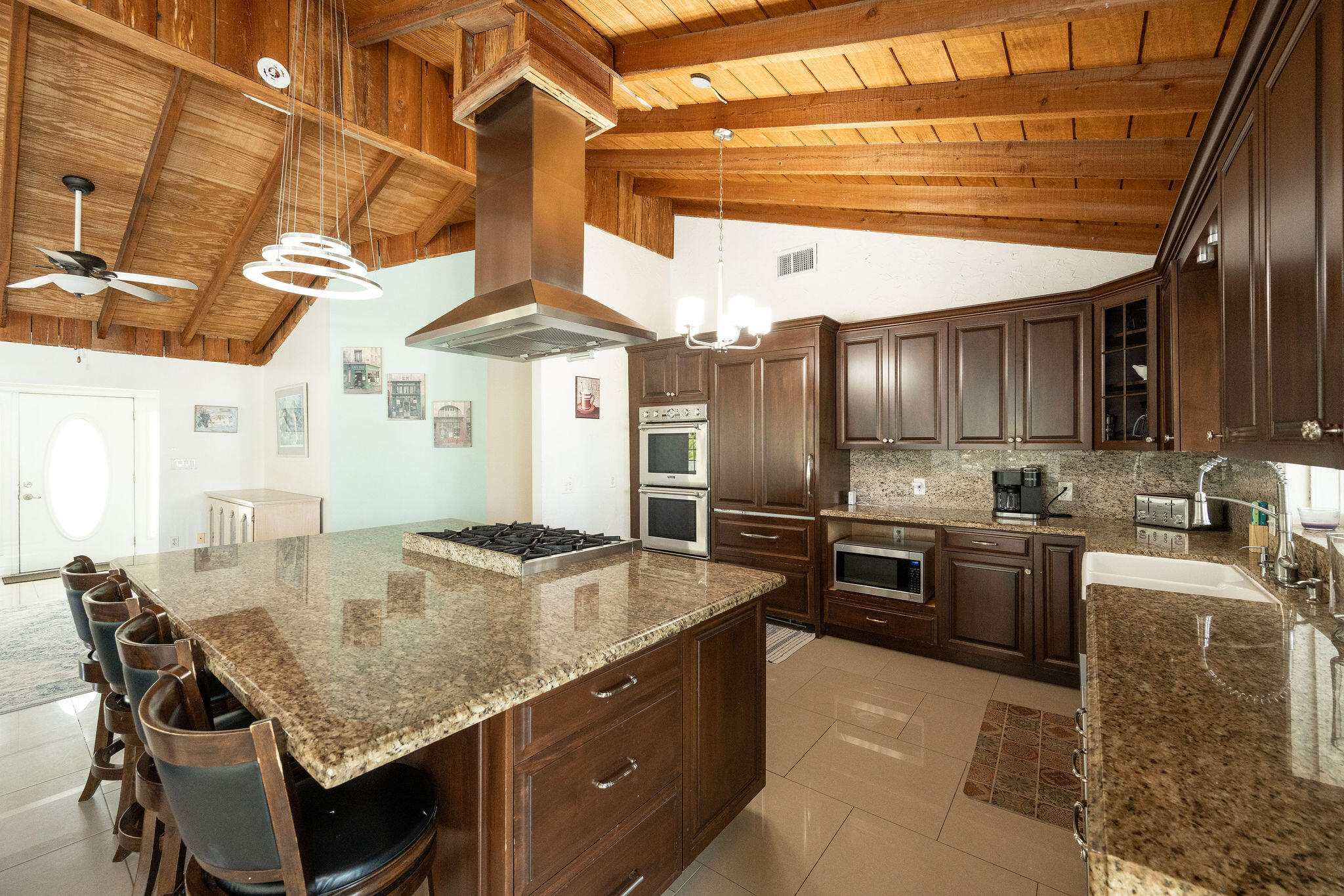 Kitchen with granite island and bar seating beneath a vaulted exposed-wood ceiling.