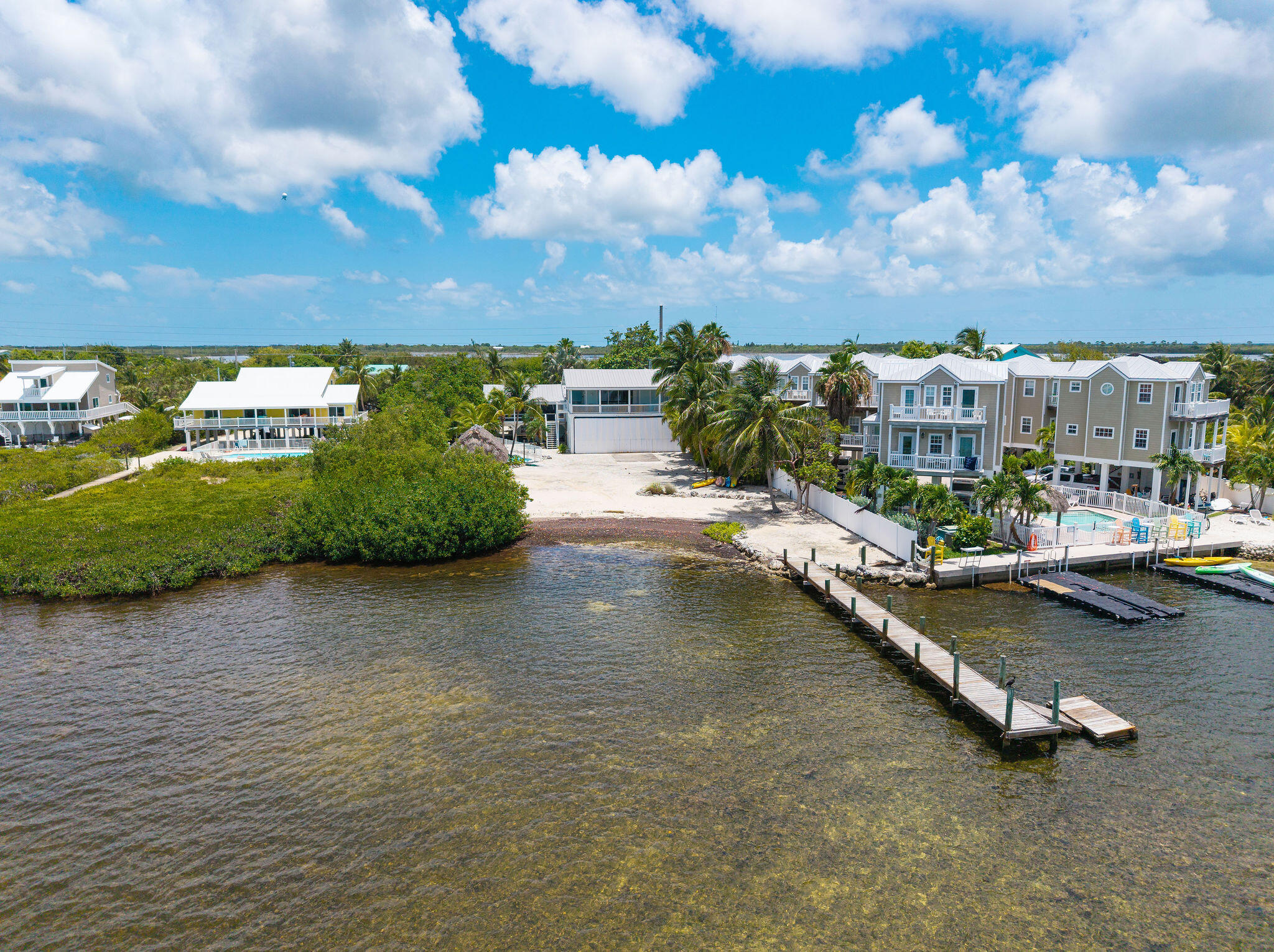Waterfront home with balconies and pool beside a long dock extending into a Florida Keys channel.