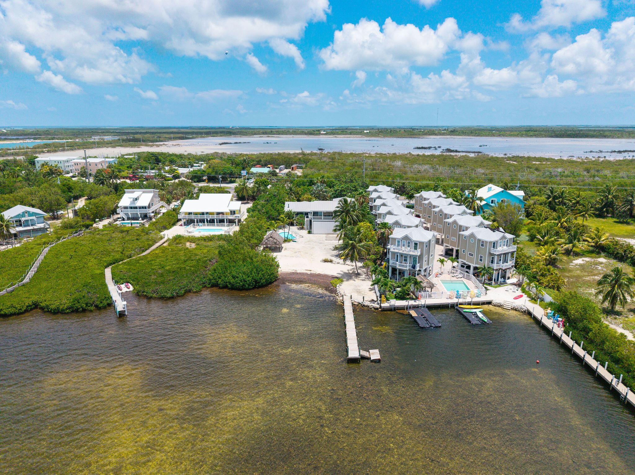 Waterfront homes and townhouses with docks and a pool along the shoreline.