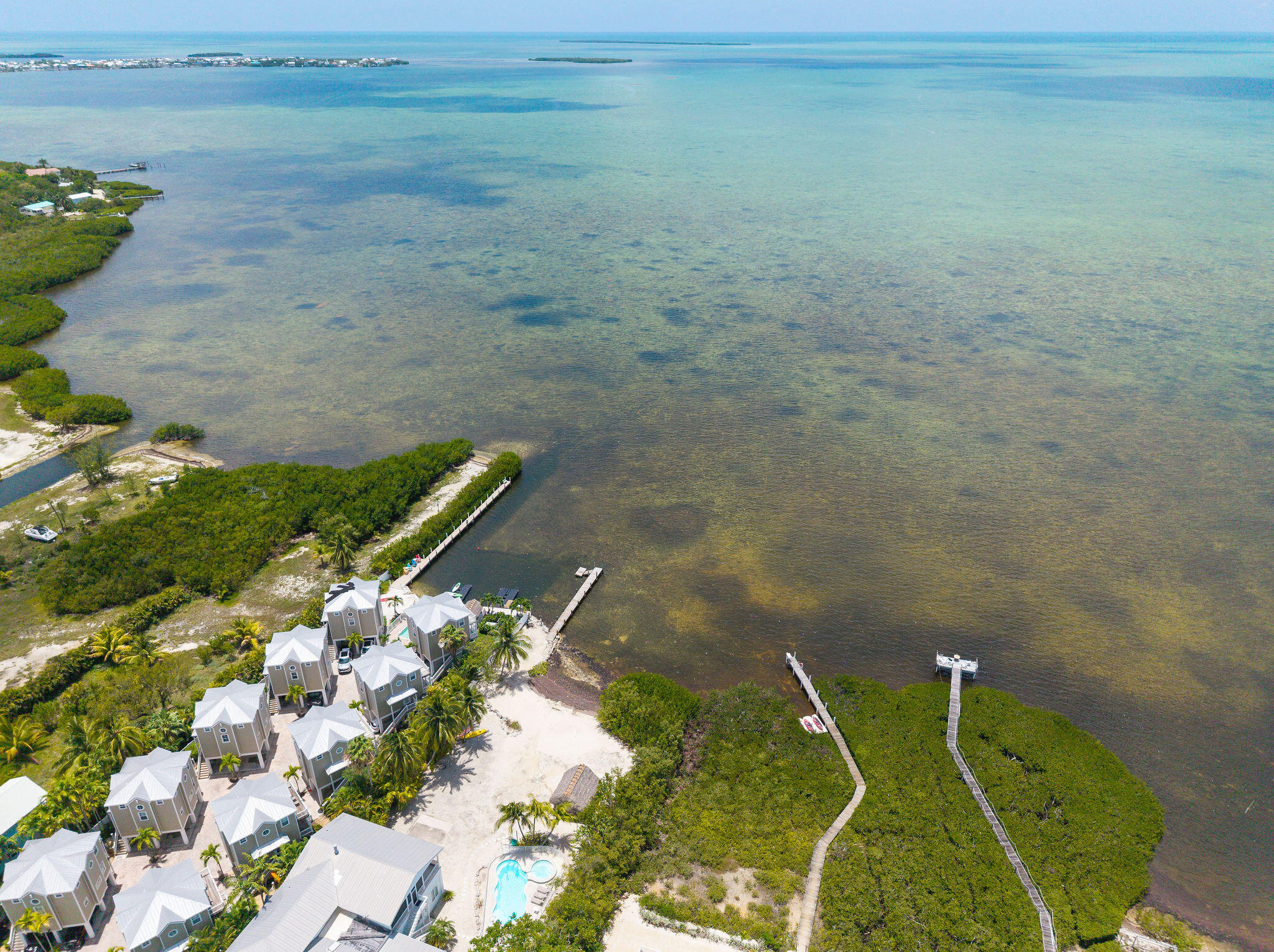 Waterfront property with clustered cottages, a pool, and long docks extending into the water.