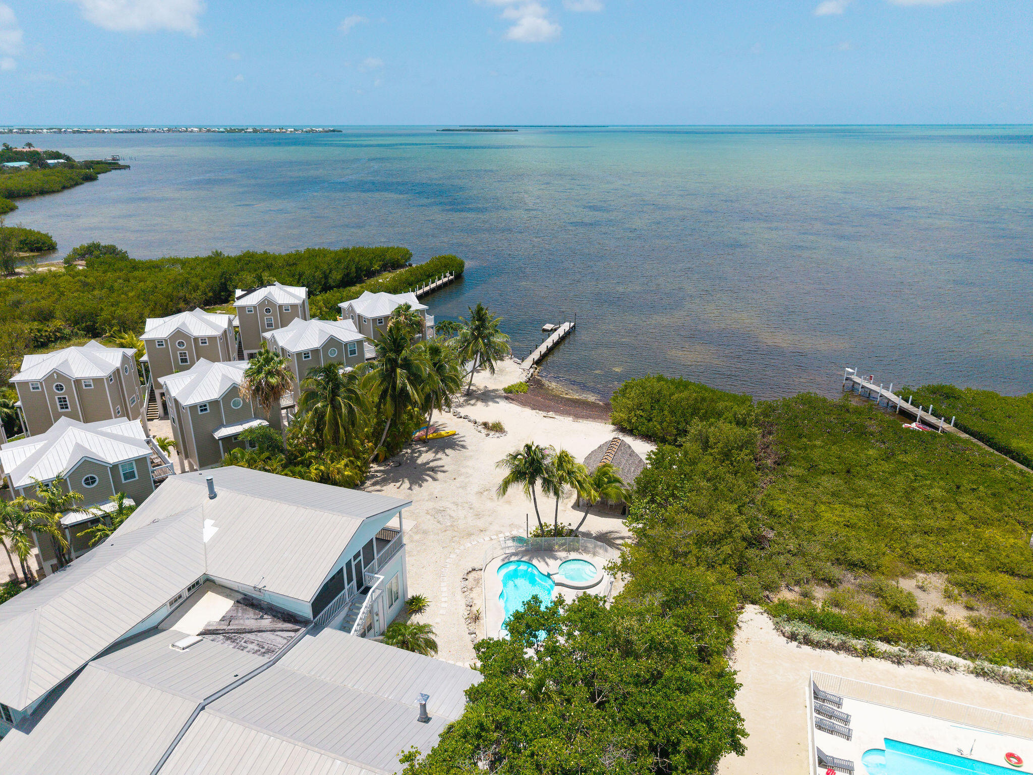 Waterfront homes, sandy beach, pools, and docks along the open water.