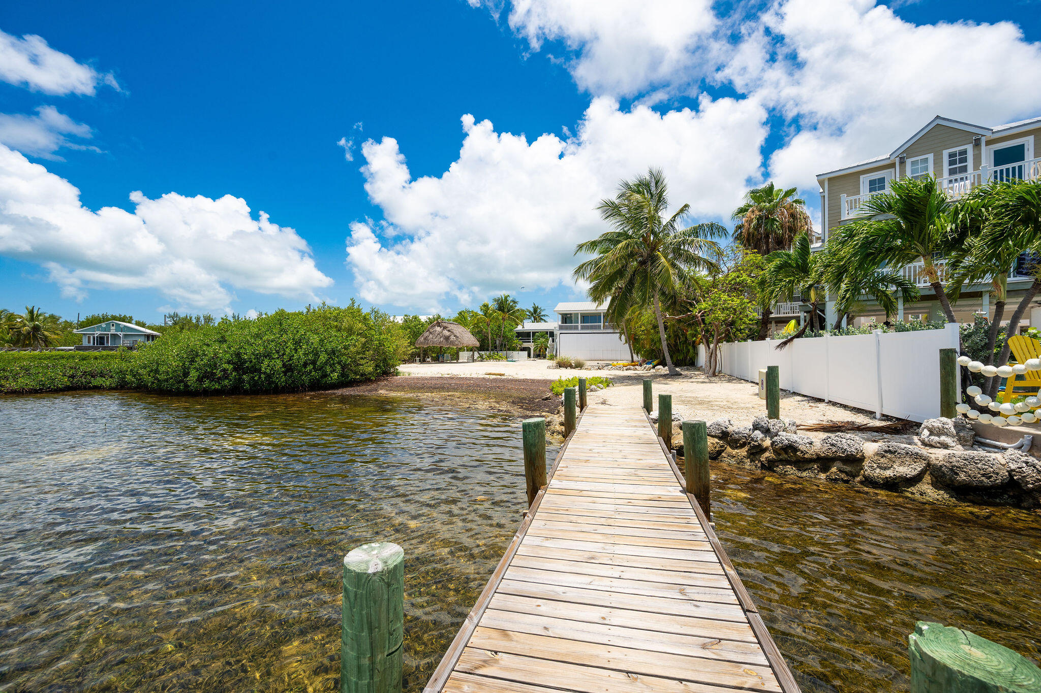 Waterfront home with a long wooden dock extending over clear shallow water.