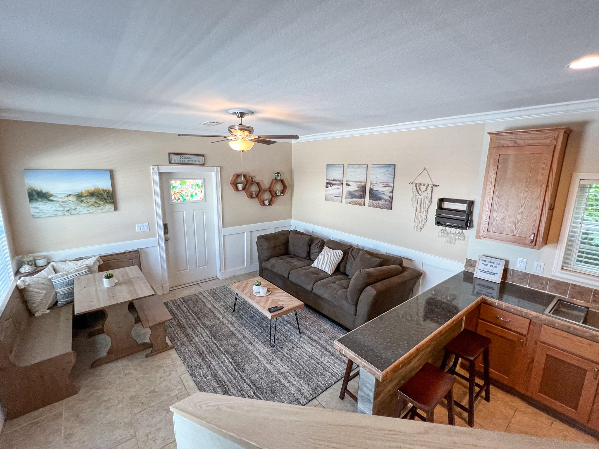 Open-plan living room and kitchen with a dark sectional, dining nook, and wood-fronted island.