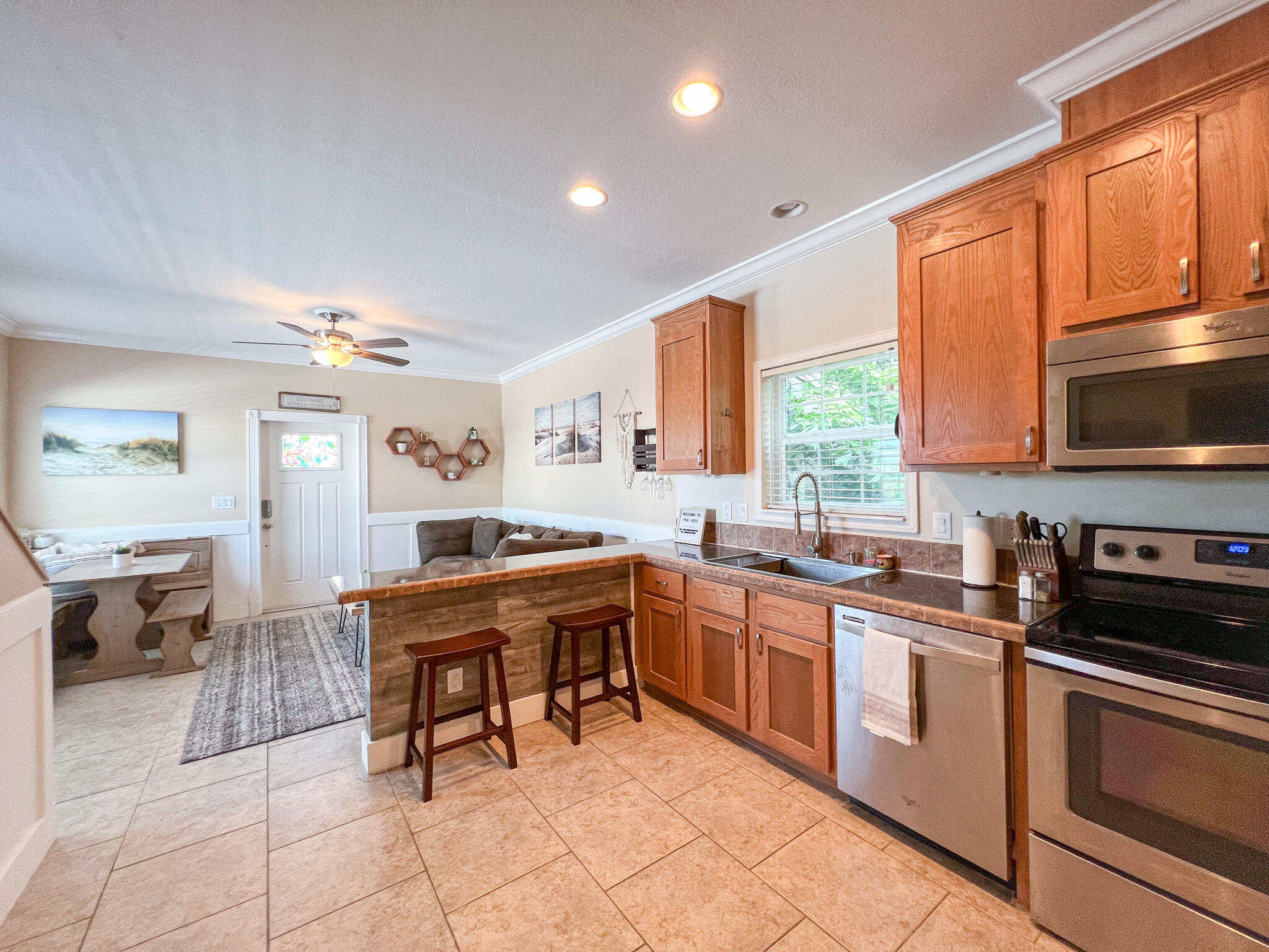 Kitchen with wood cabinets, stainless steel appliances, and a breakfast bar opening to dining and living areas.