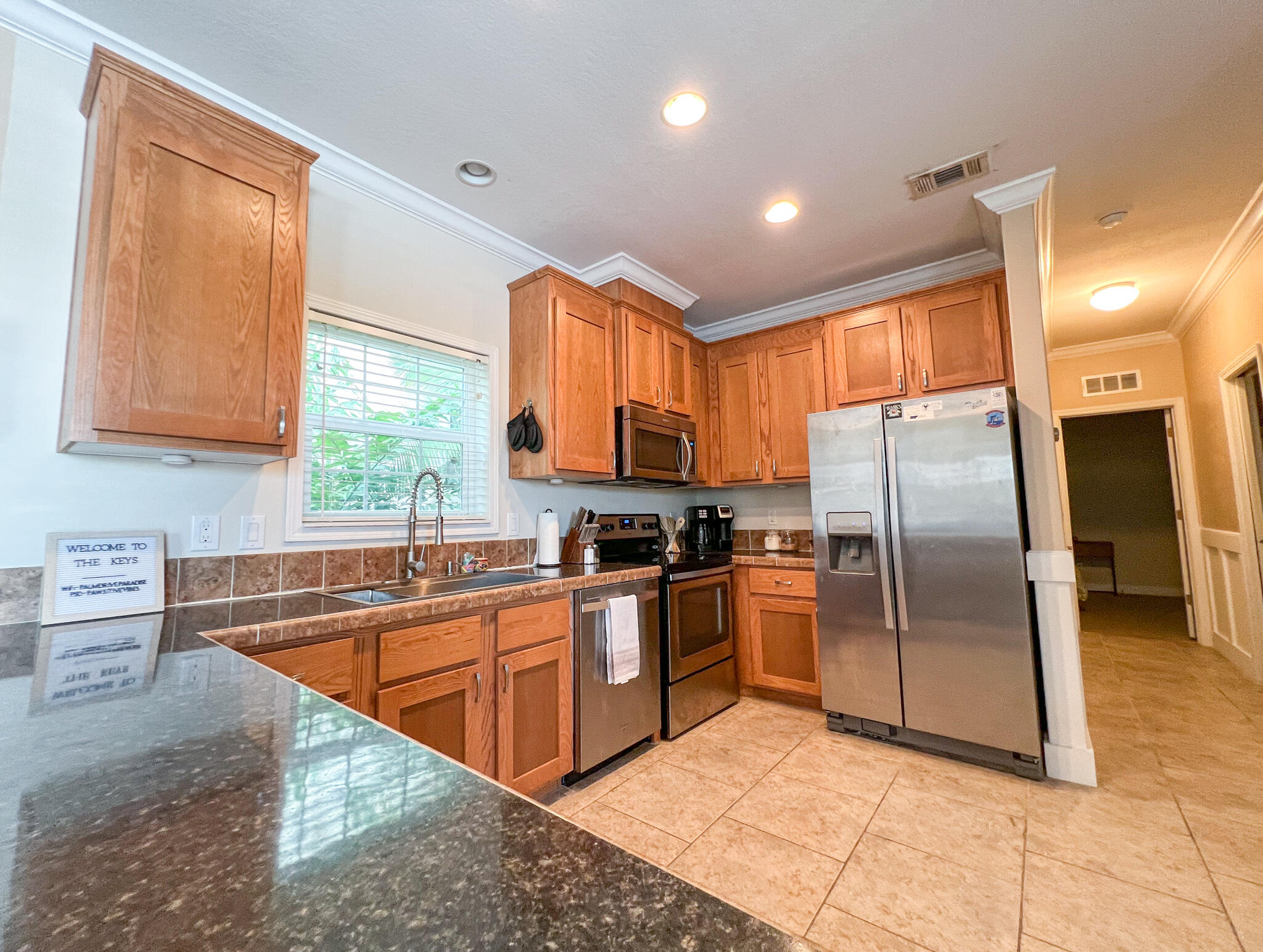 Kitchen with warm wood cabinets, dark stone island countertop, and stainless steel appliances.