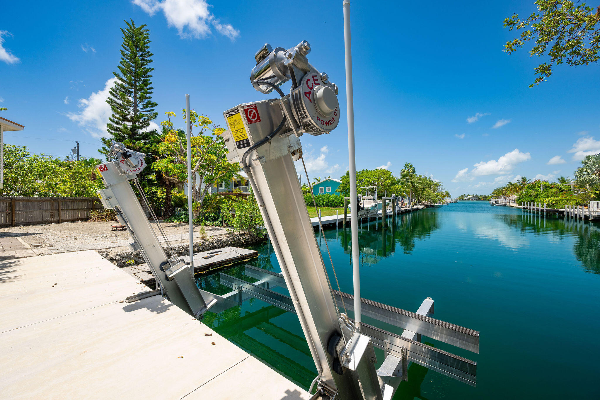 Canal-side boat lift and dock overlooking a turquoise residential waterway.