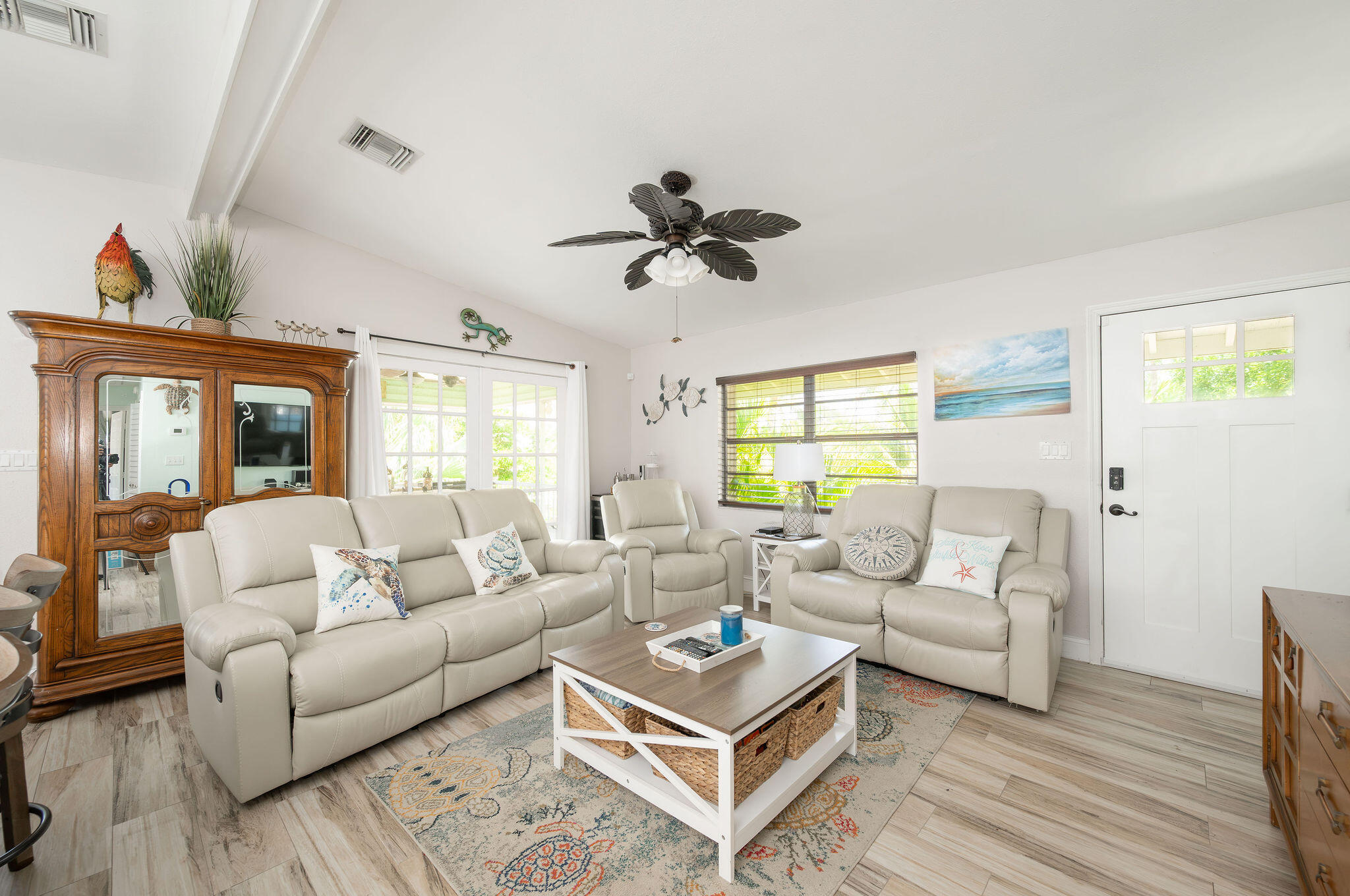 Living room with cream leather seating, a patterned rug, and bright windows.