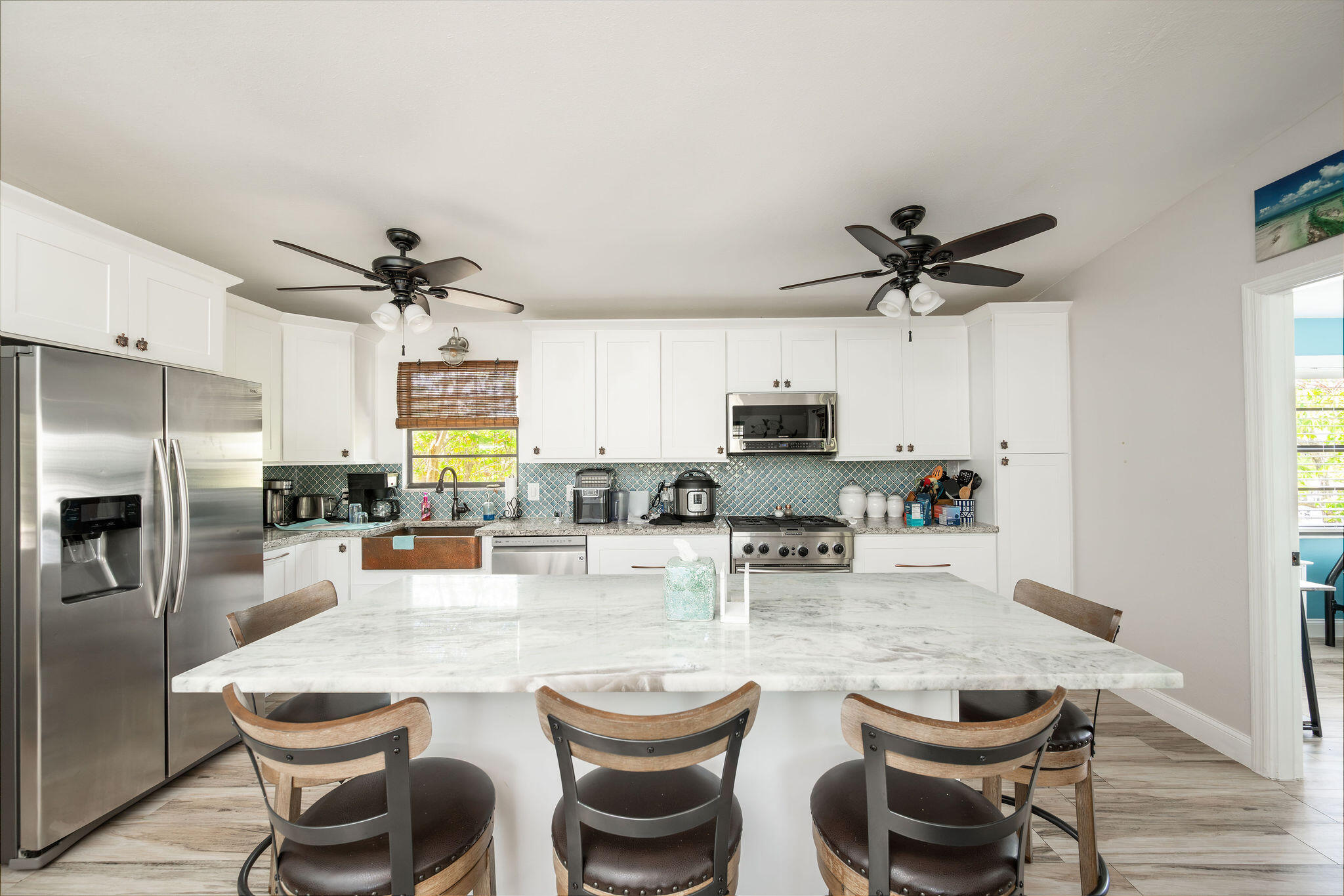Kitchen with a large marble island, white cabinets, and blue patterned backsplash.