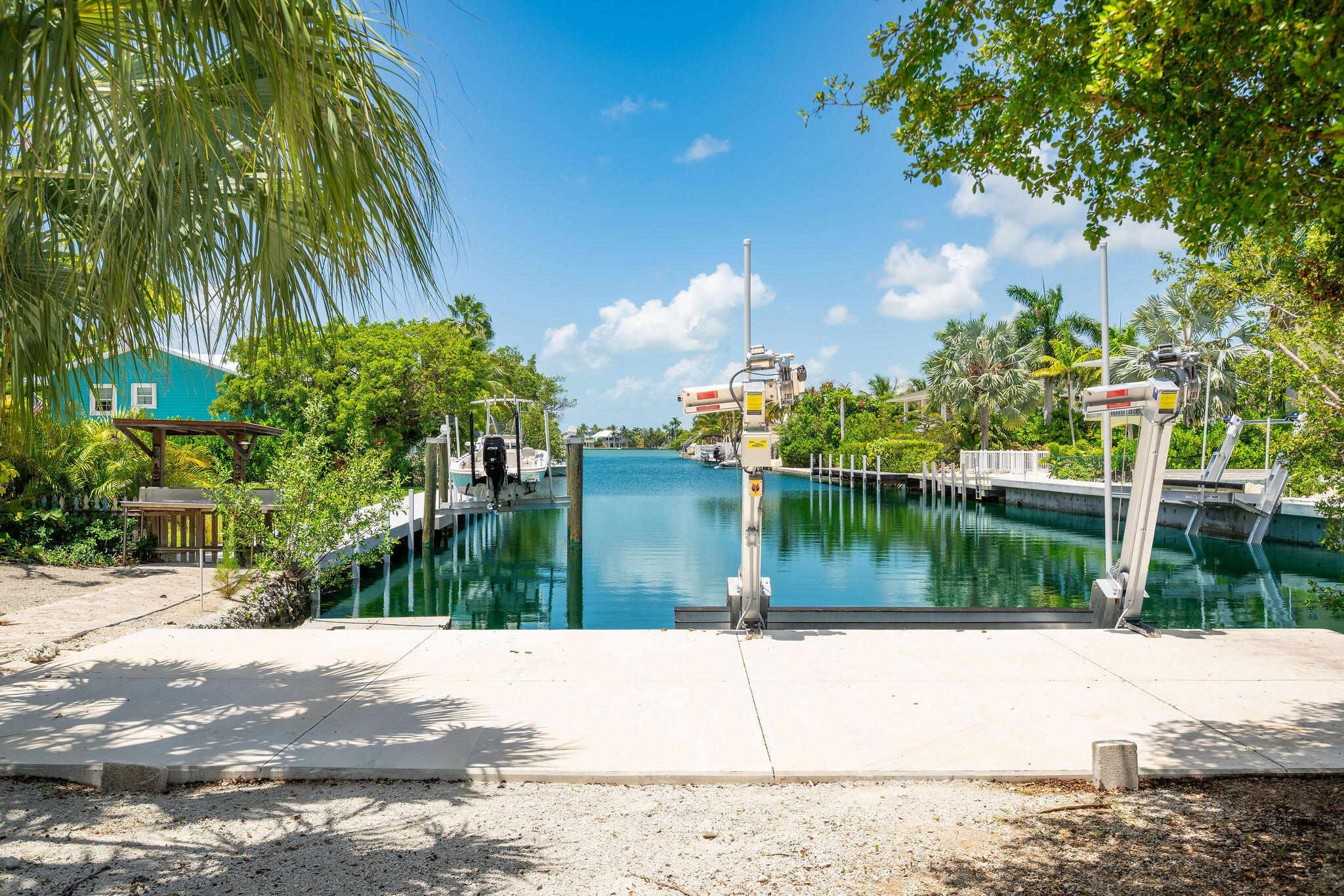 Waterfront boat basin with multiple boat lifts, dock platforms, and a concrete launch area.