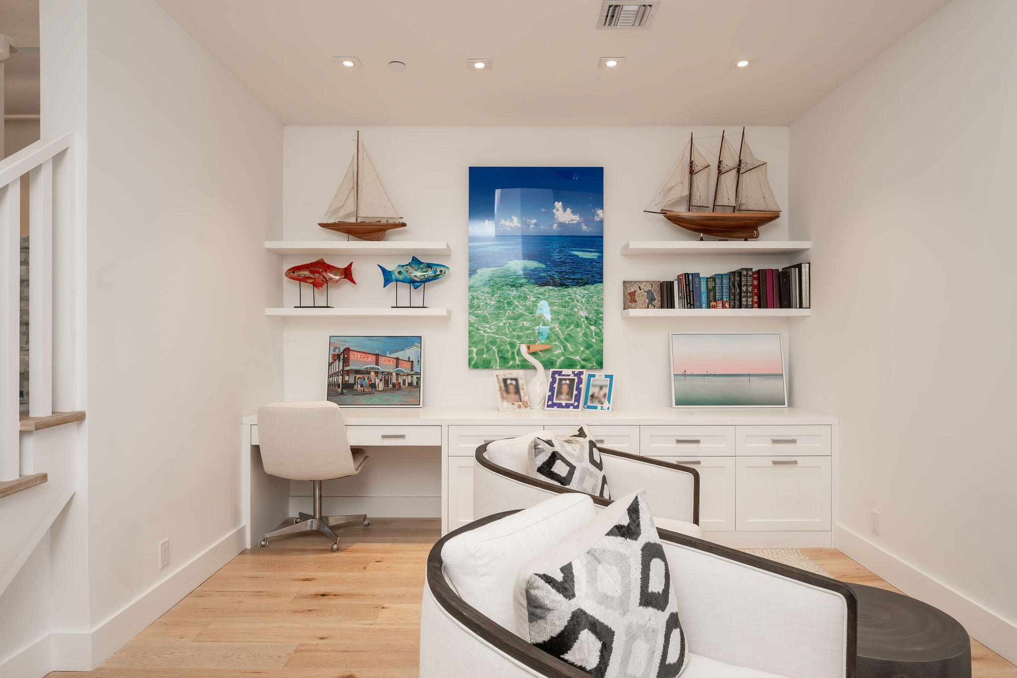 Home office with a built-in desk, coastal decor, and two lounge chairs.