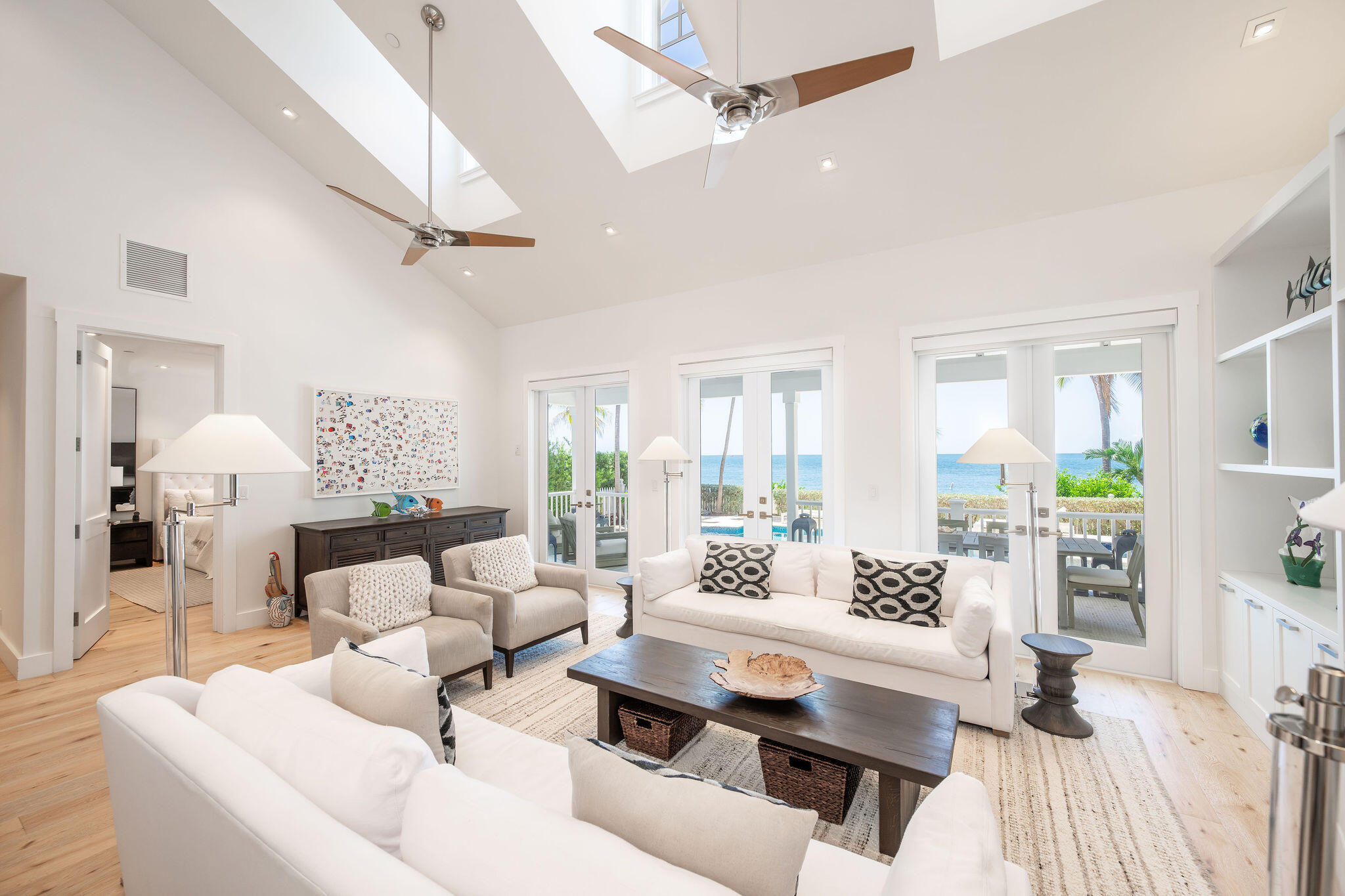 Living room with vaulted ceiling and ocean views through glass doors.