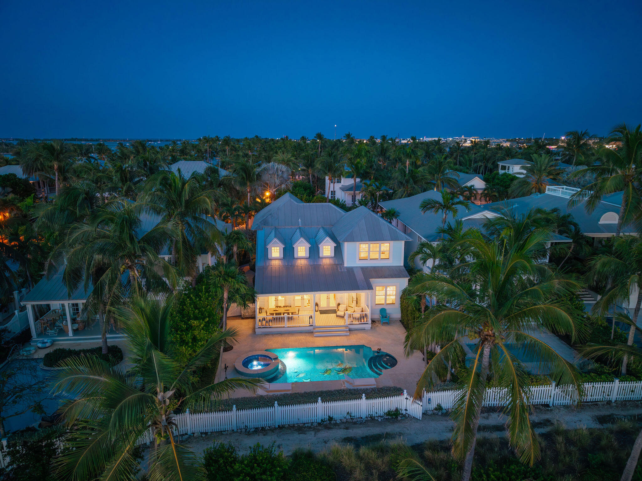 Aerial view of Key West home and illuminated pool surrounded by palm trees at night