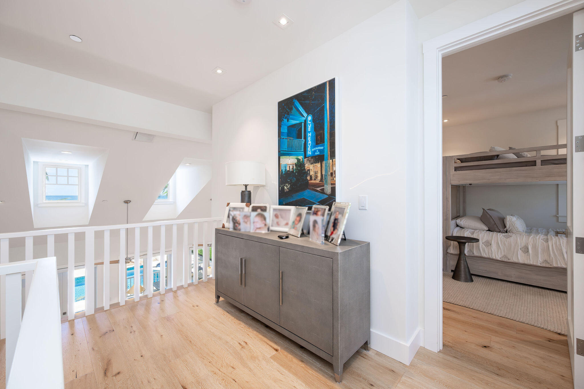 Upstairs landing overlooking a pool, with a gray console and a bunk bed visible through the bedroom doorway.