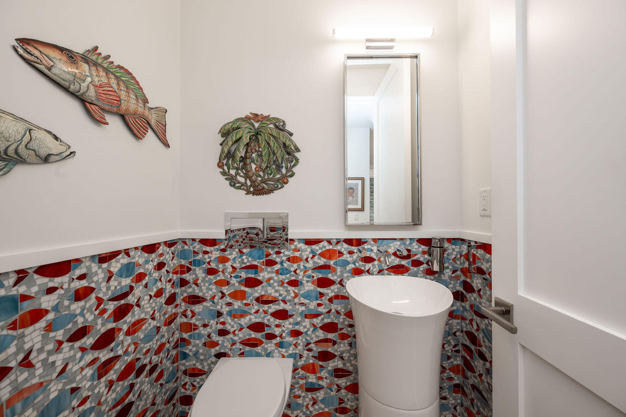 Bathroom with colorful fish-pattern mosaic tile, a pedestal sink, and fish-themed wall decor.