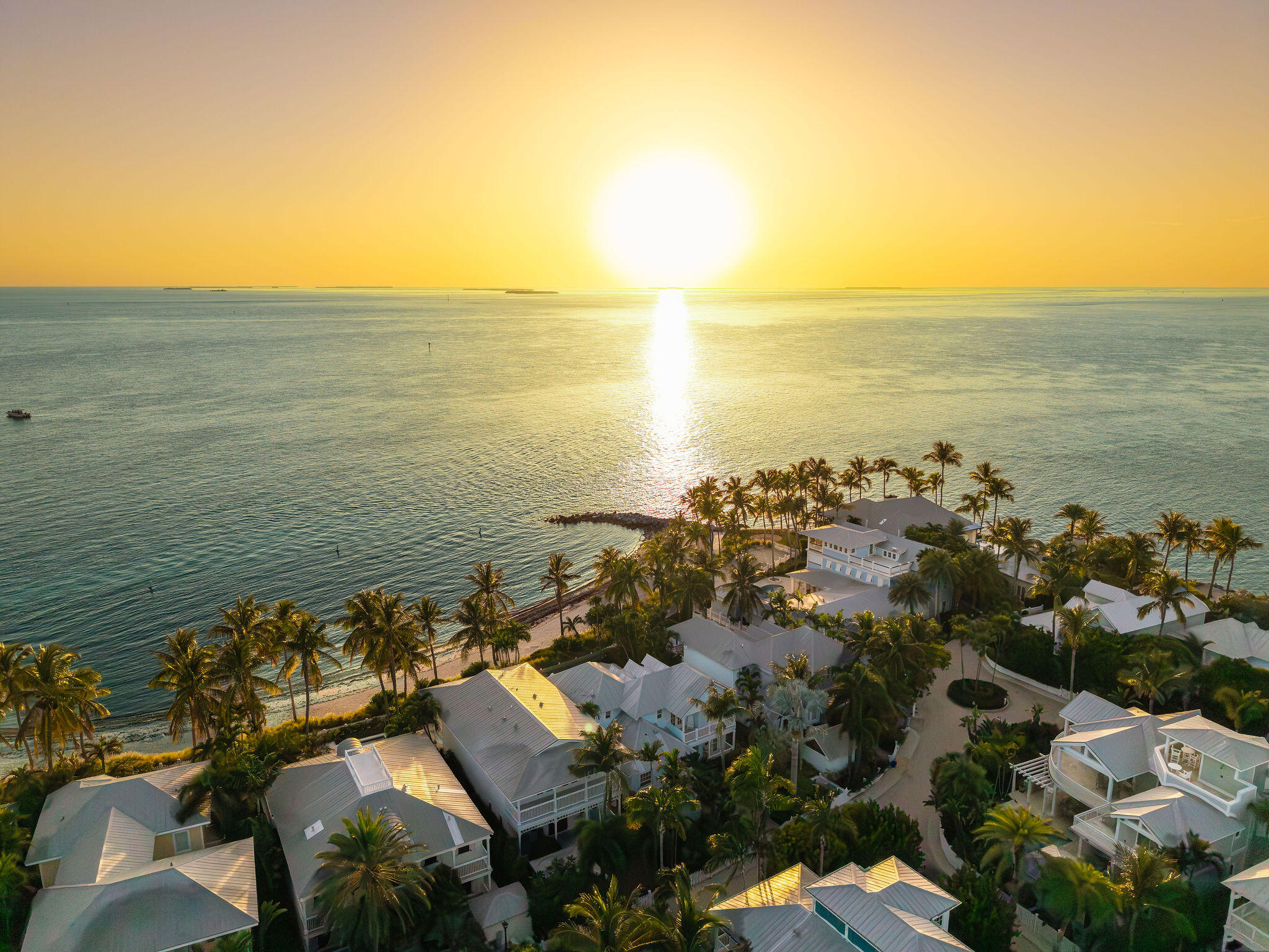 Aerial view of Sunset Key homes along the shore at sunset, with palms and ocean.