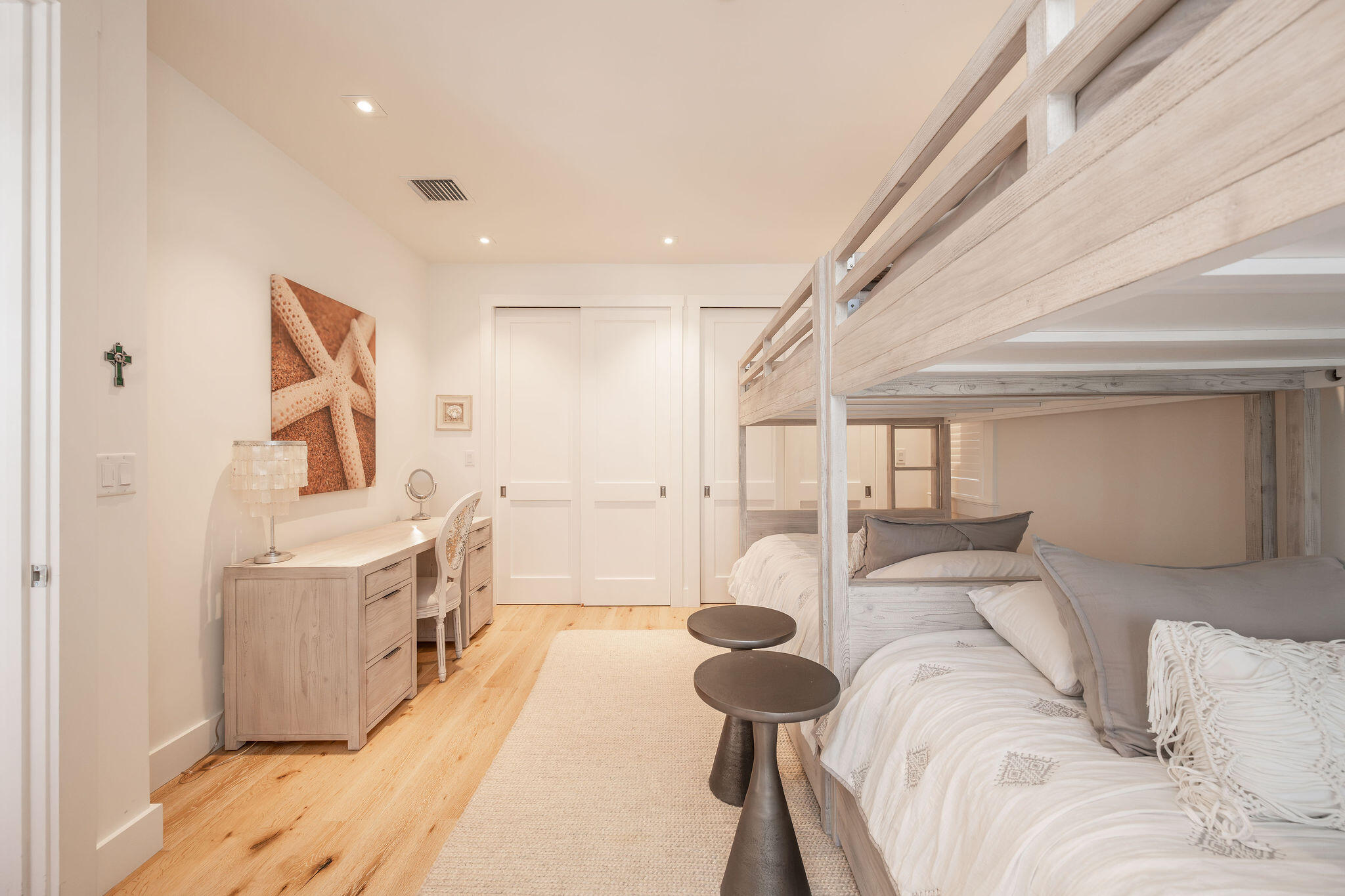 Bedroom with a light wood bunk bed, white bedding, and starfish wall art.