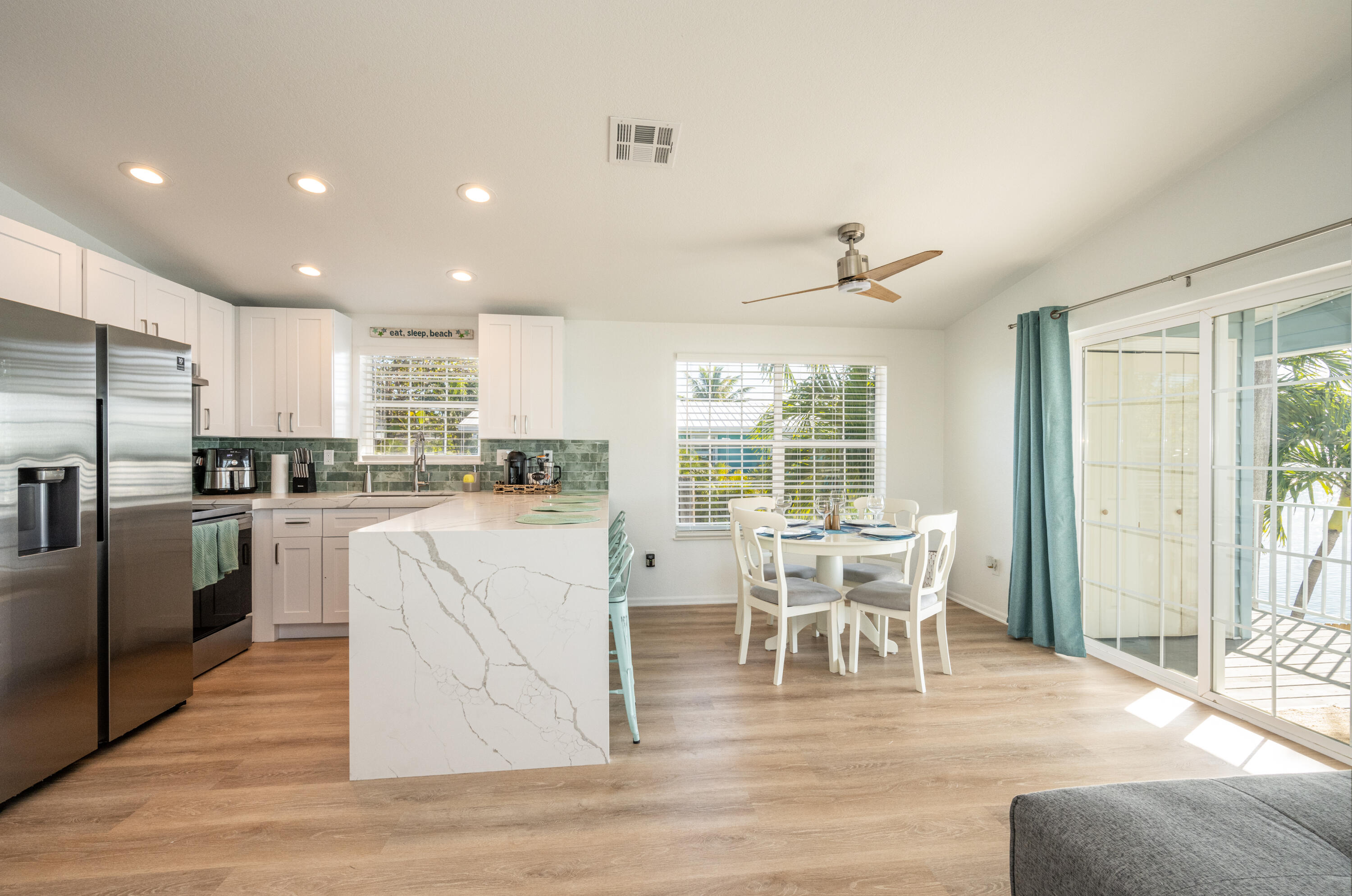 Open kitchen and dining area with a marble-look island and sliding glass doors beside the table.