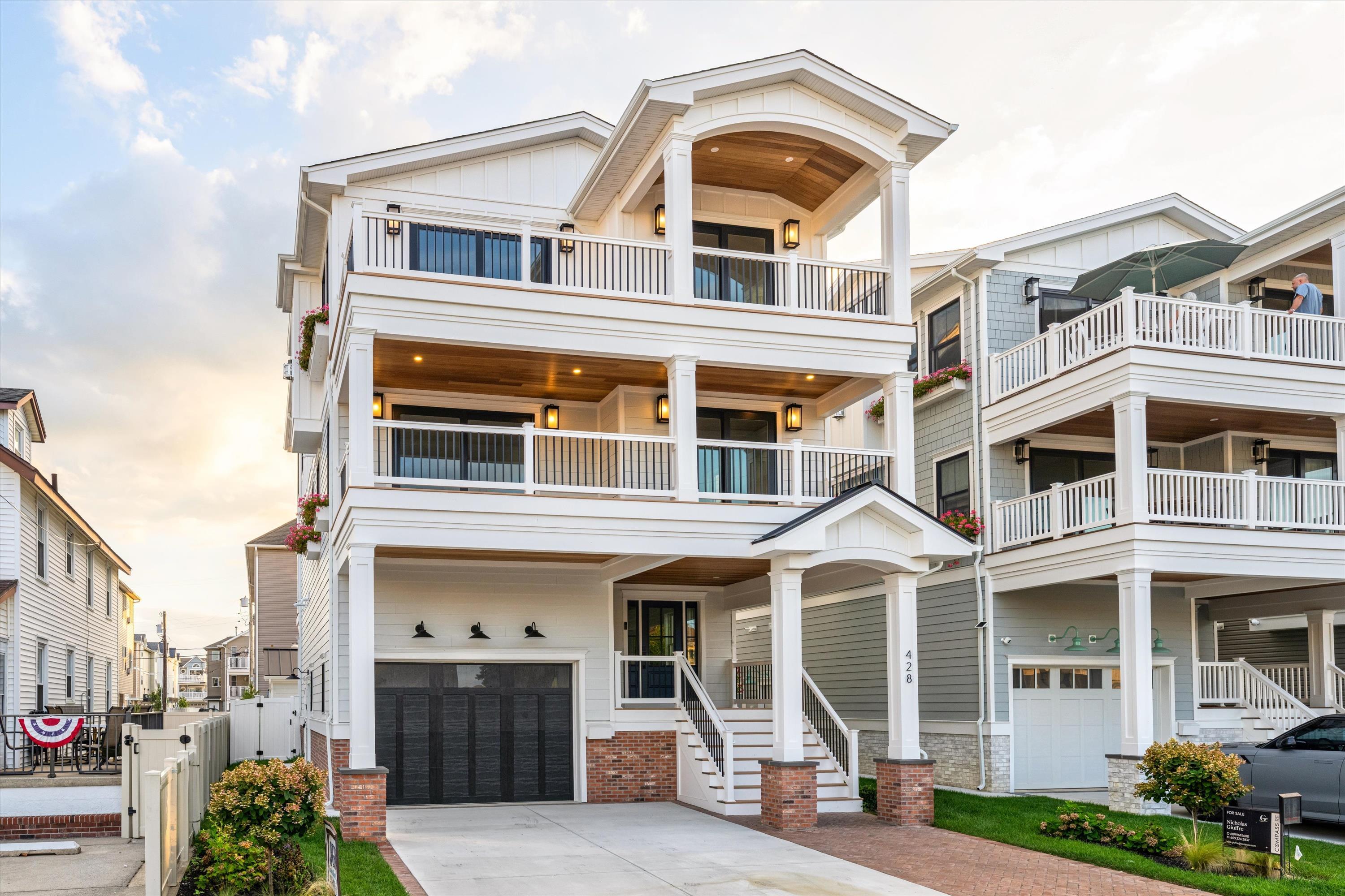 Three-story white coastal home with stacked balconies, wood-paneled porch ceilings, and a garage.