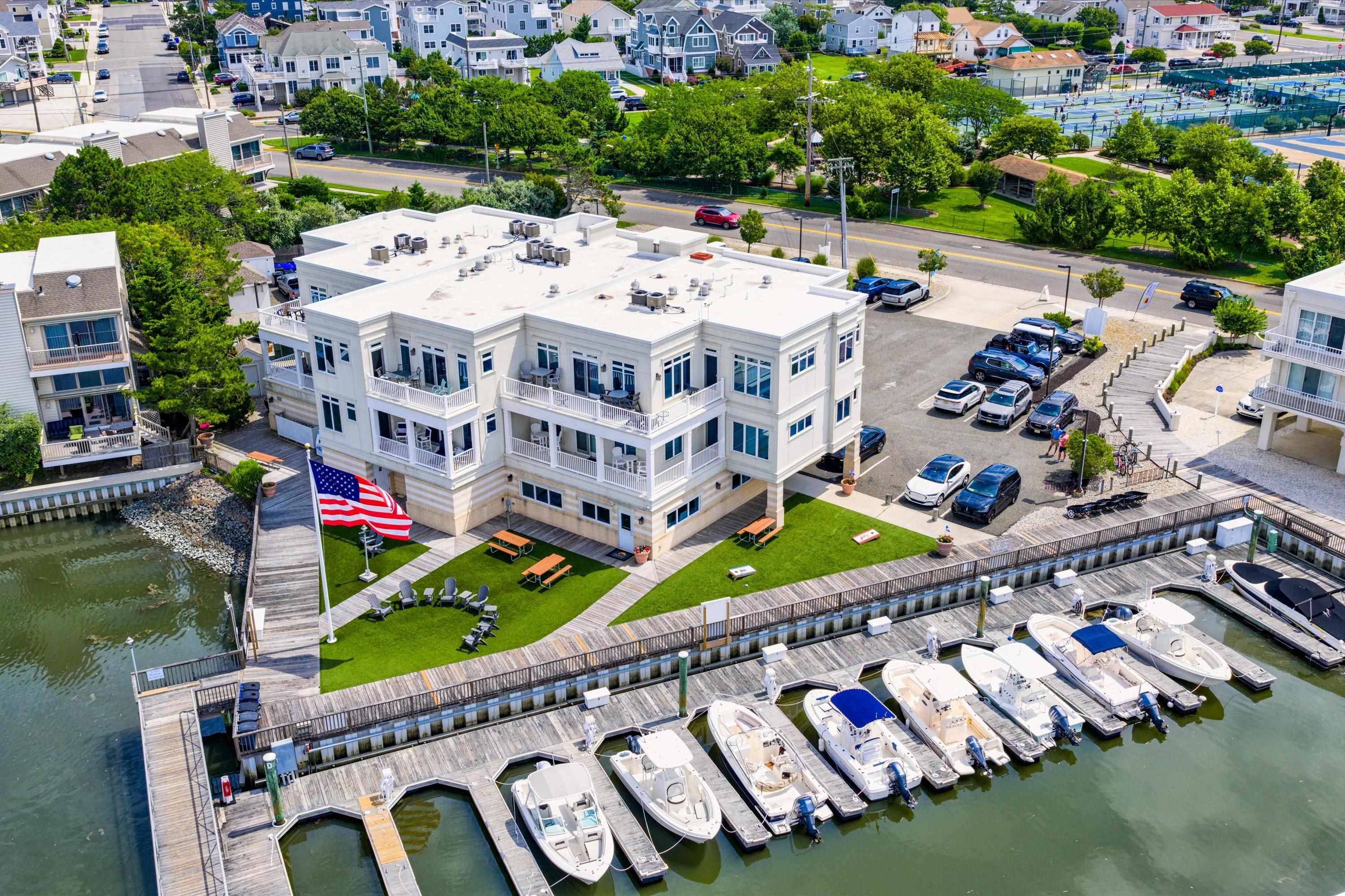 Waterfront condominium building with balconies, a lawn, and boats docked along the marina.