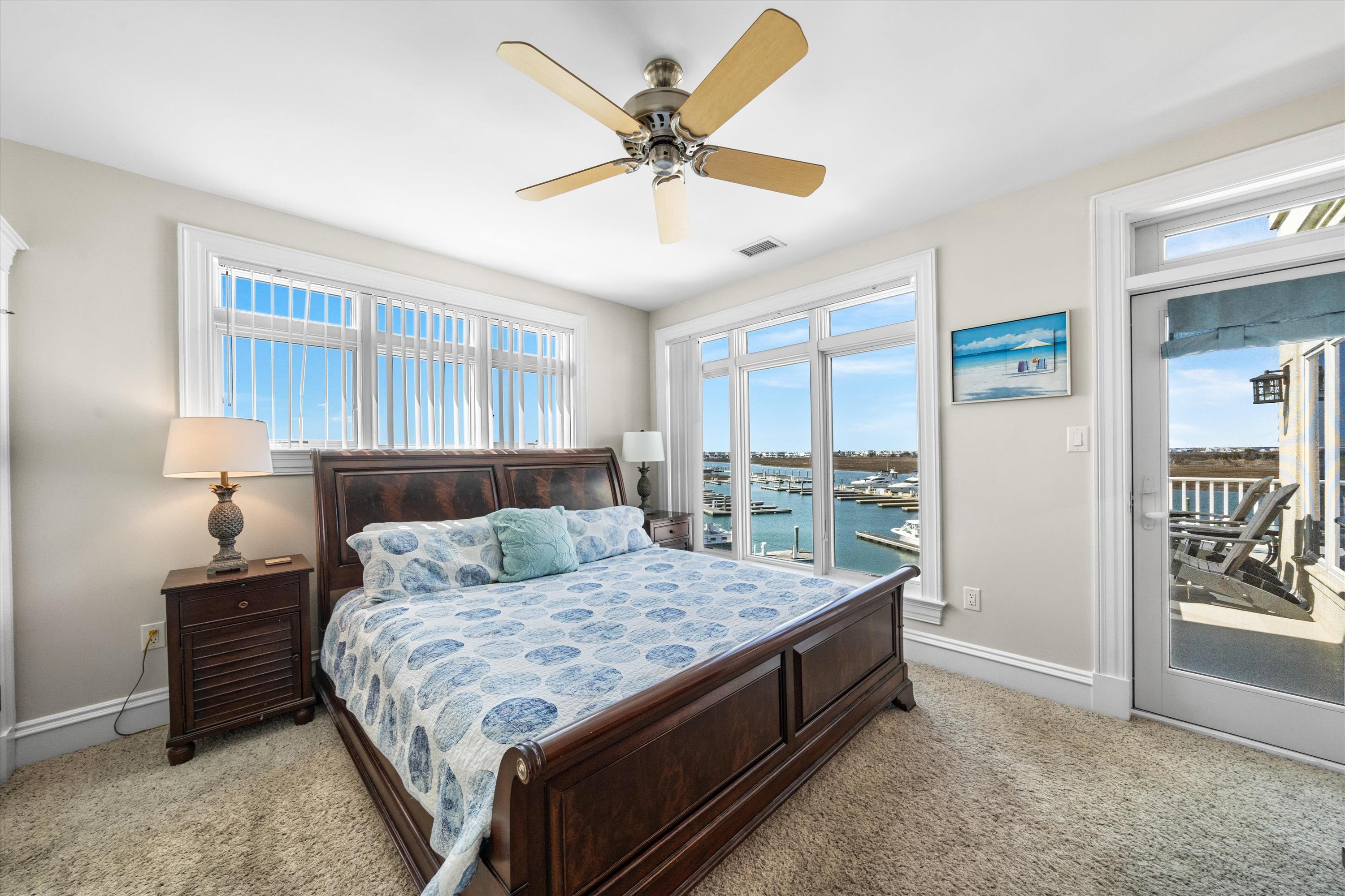 Bedroom with a dark wood bed and large windows overlooking a marina.