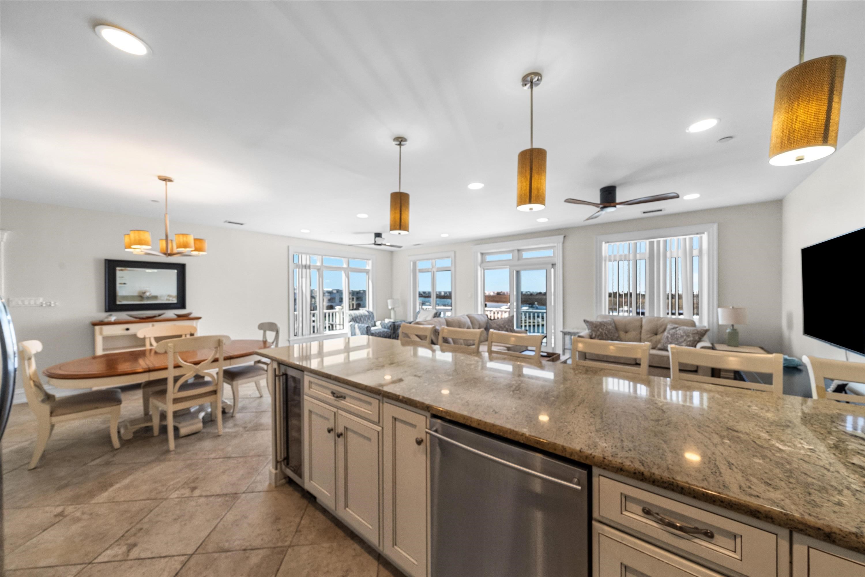 Open-plan kitchen and living room with a large stone island and windows overlooking the water.