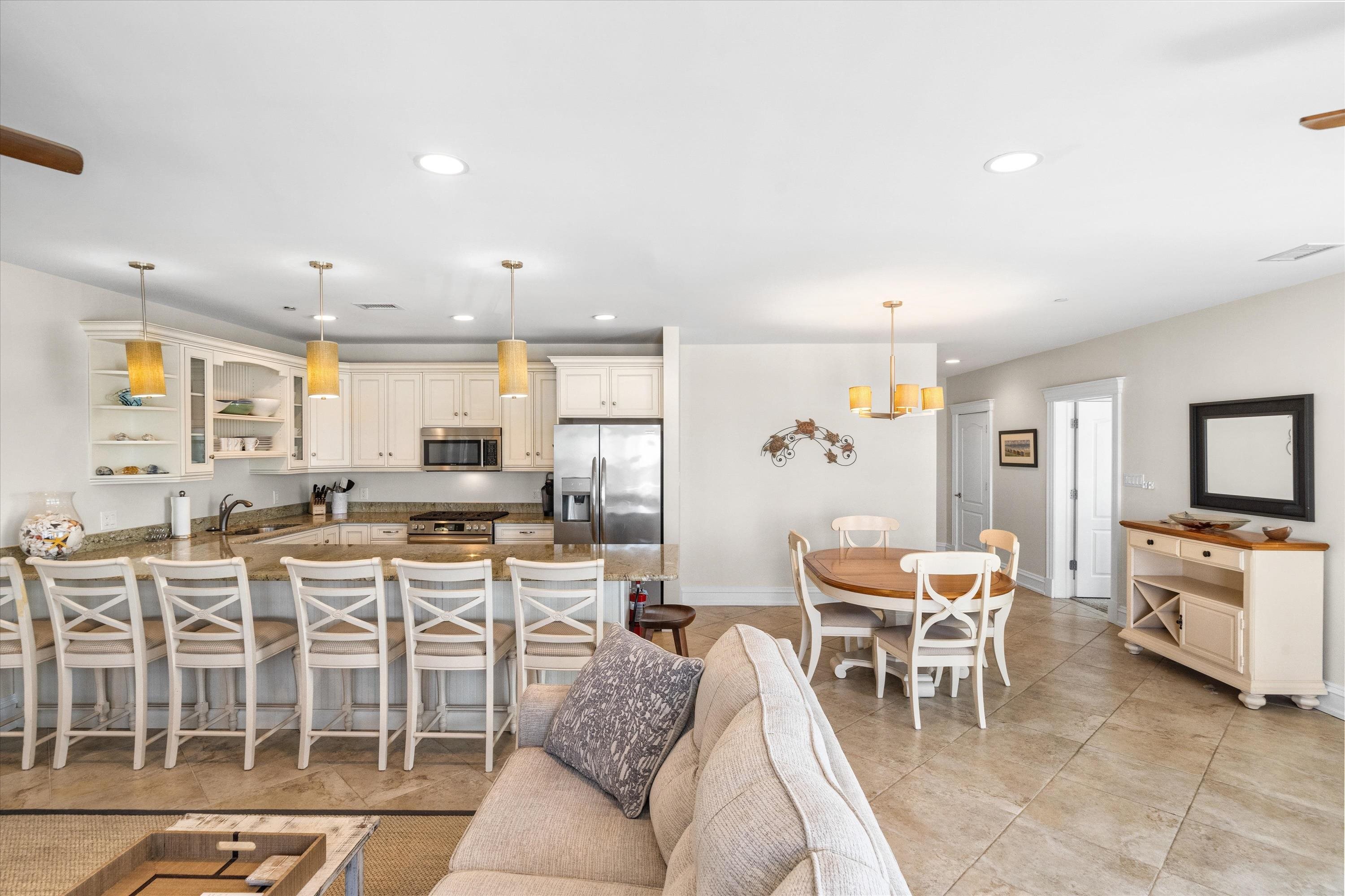 Open-plan kitchen and dining area with white cabinets, granite breakfast bar, and round table.