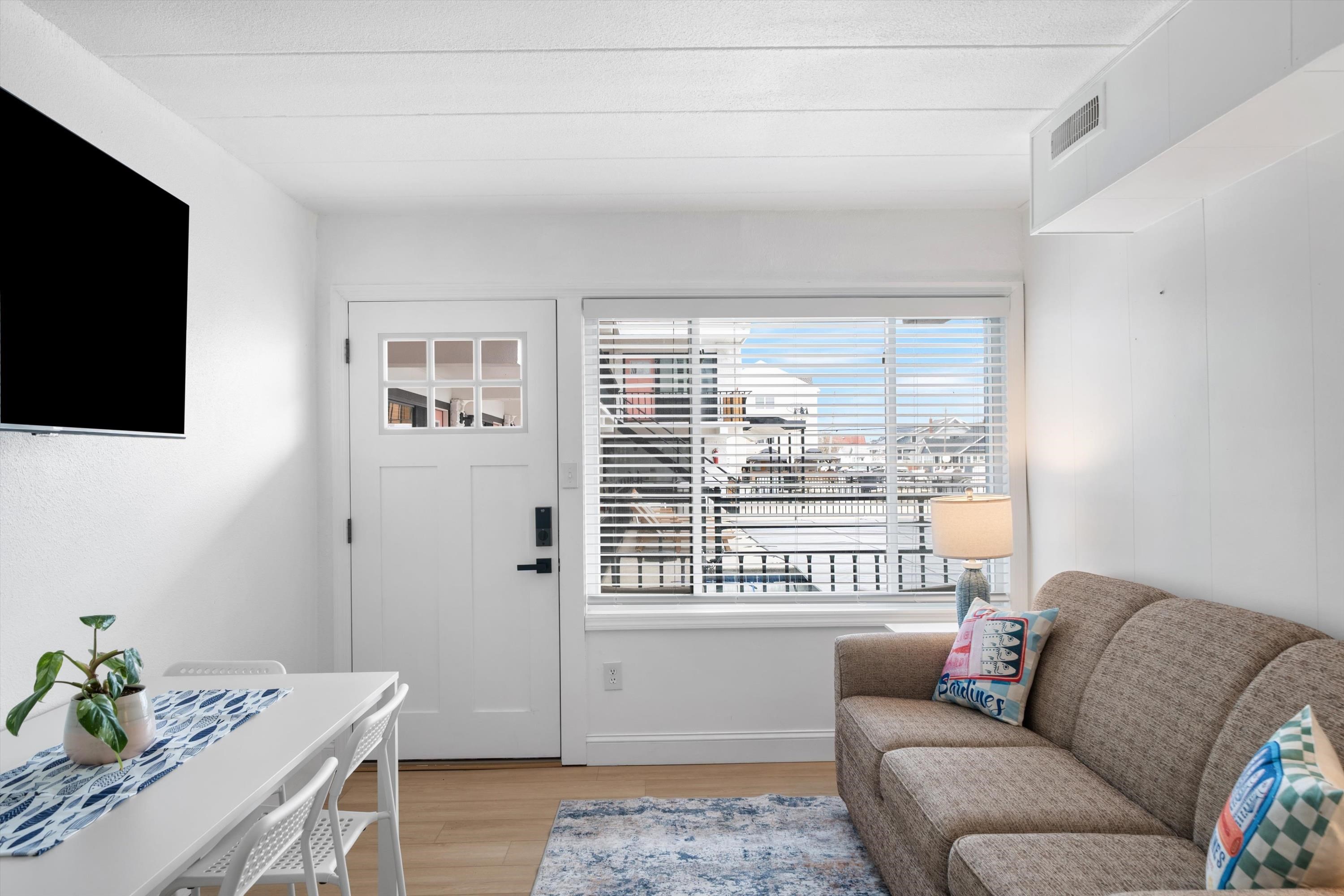 Furnished living and dining area with a gray sofa and marina visible through the window.