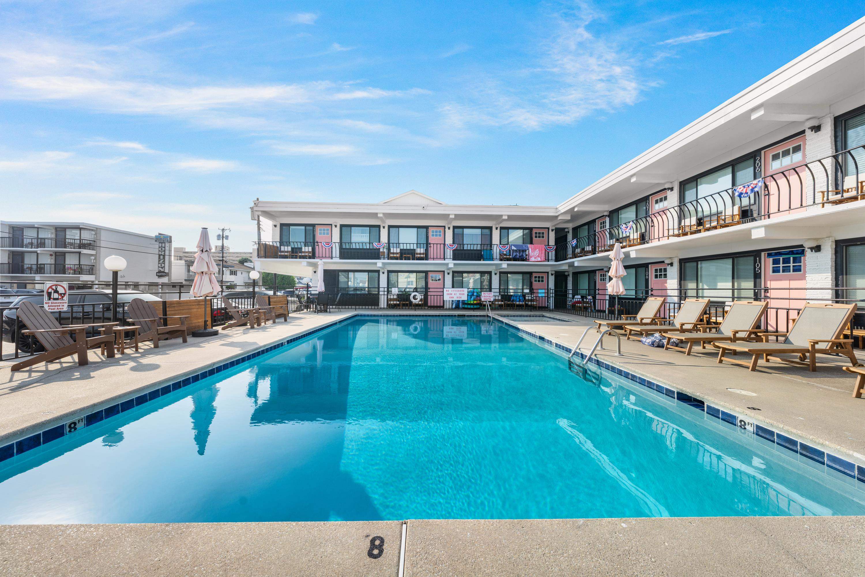 Outdoor pool surrounded by two-story motel balconies and lounge chairs.