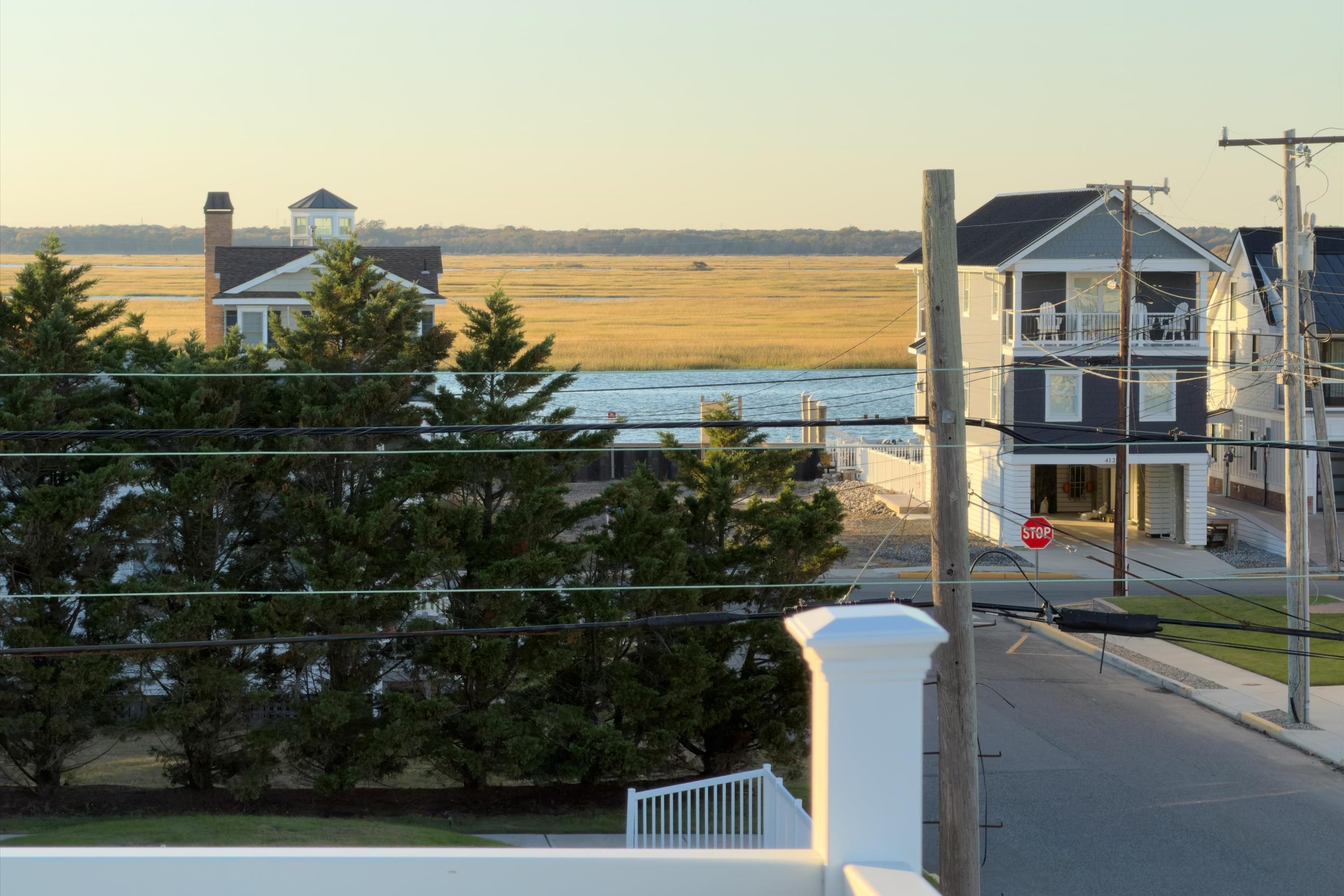 Coastal neighborhood and marsh viewed from a deck, with water and neighboring houses.