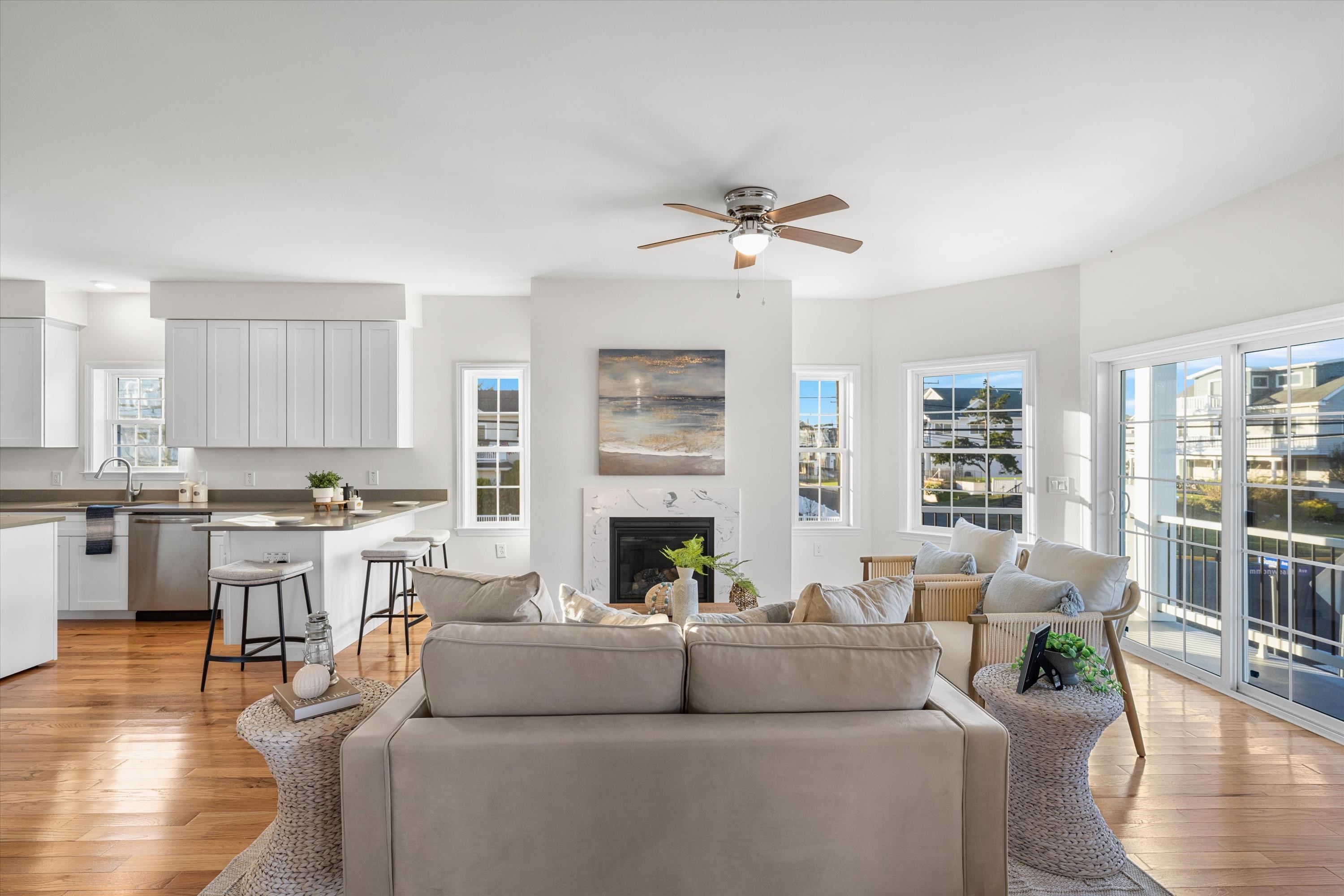 Open-plan living room and kitchen with a fireplace, wood floors, and sliding doors to the deck.
