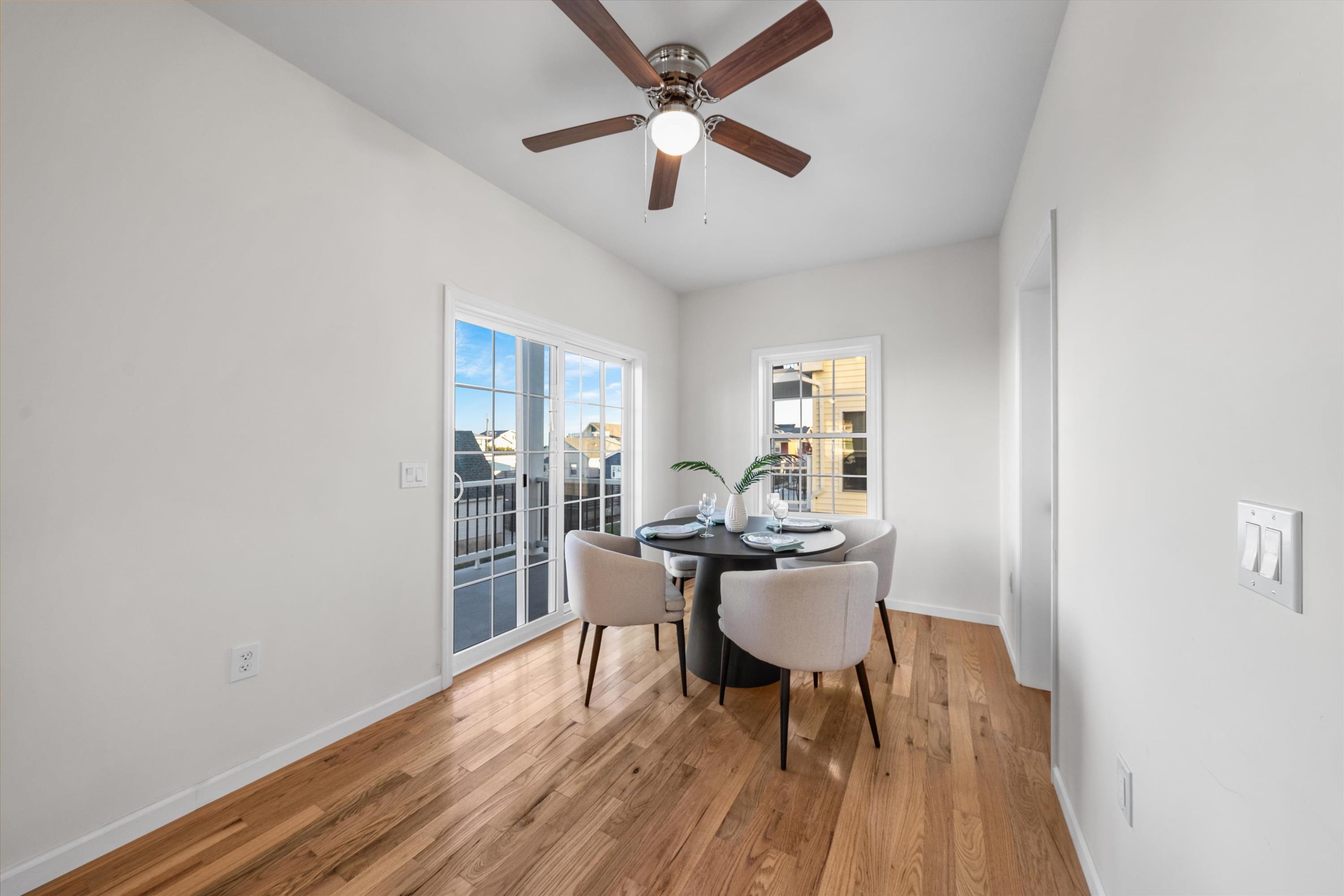 Dining area with a round table, four chairs, hardwood floors, and sliding doors to a balcony.