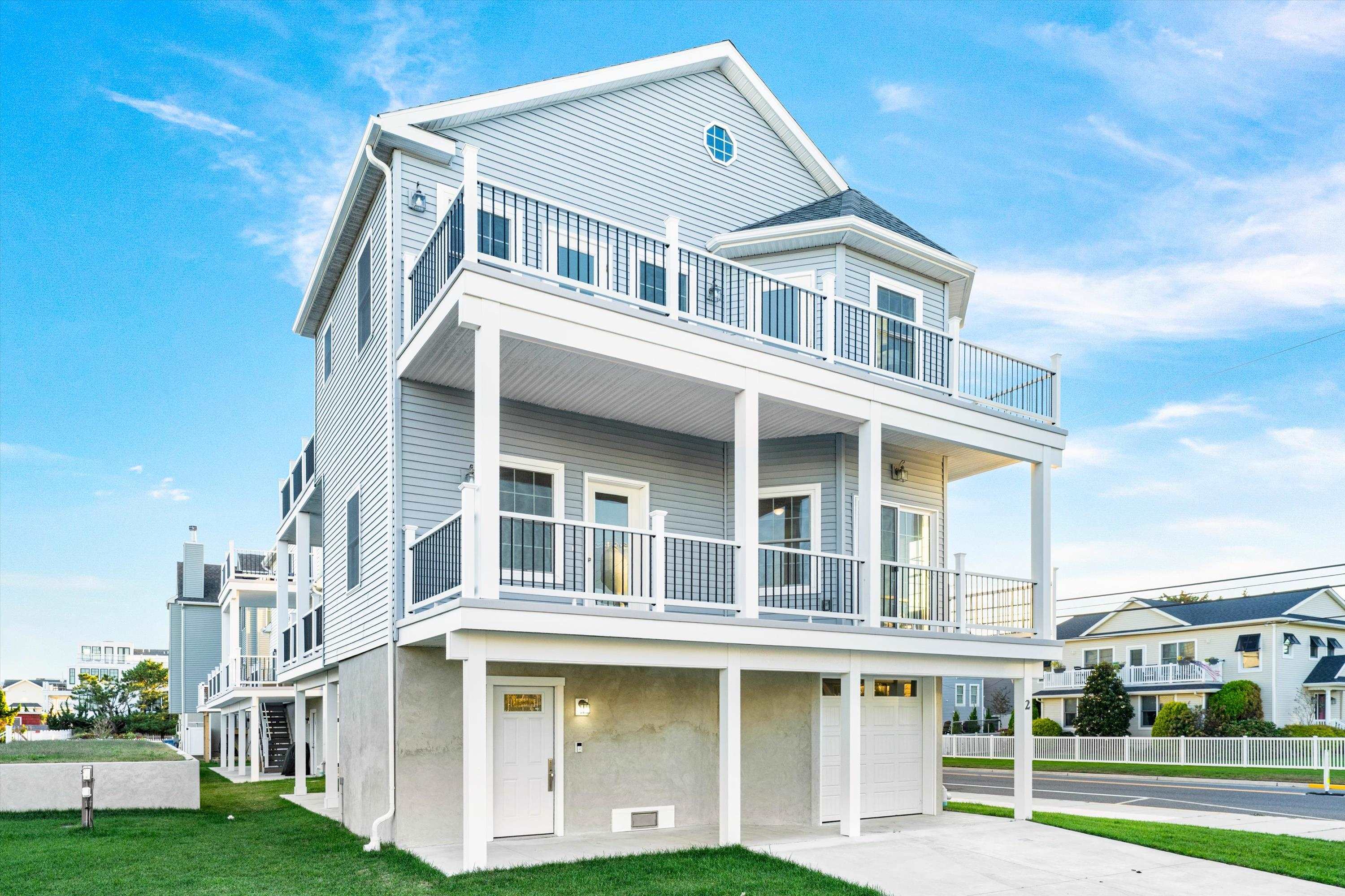 Raised coastal-style home with gray siding, two covered balconies, and a garage below.