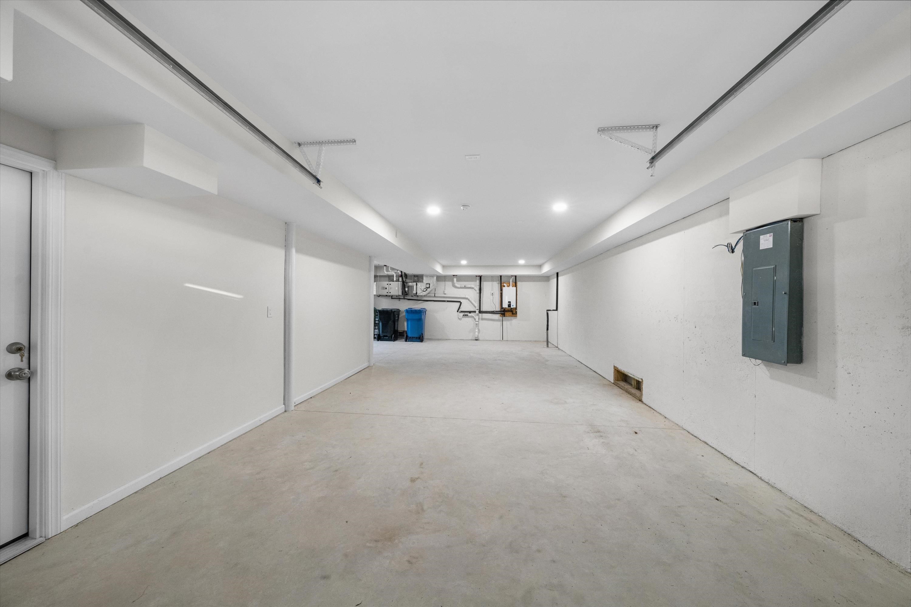 Empty garage with a concrete floor, overhead door tracks, and an electrical panel.