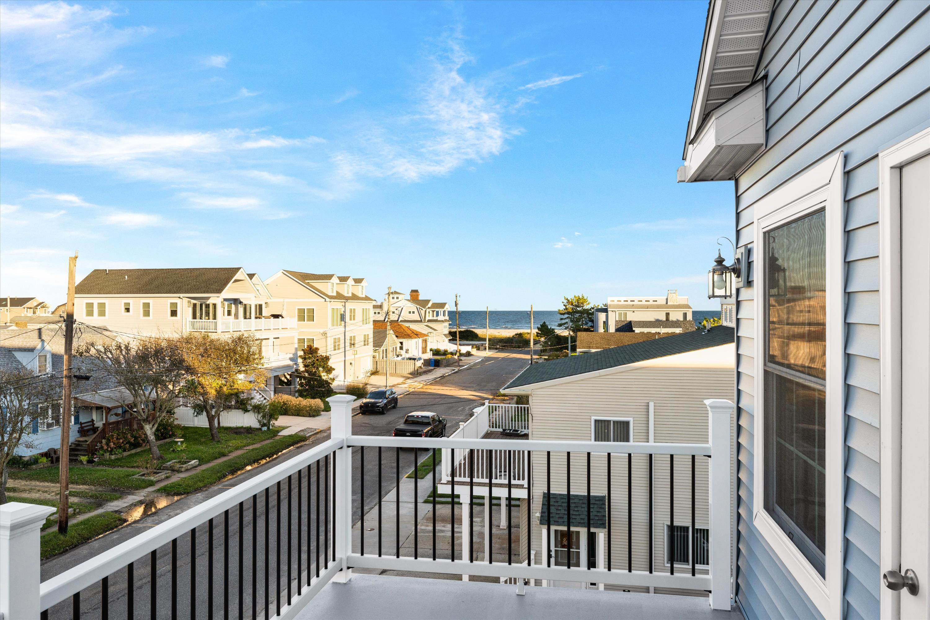 Balcony overlooking coastal homes, a neighborhood street, and the ocean.