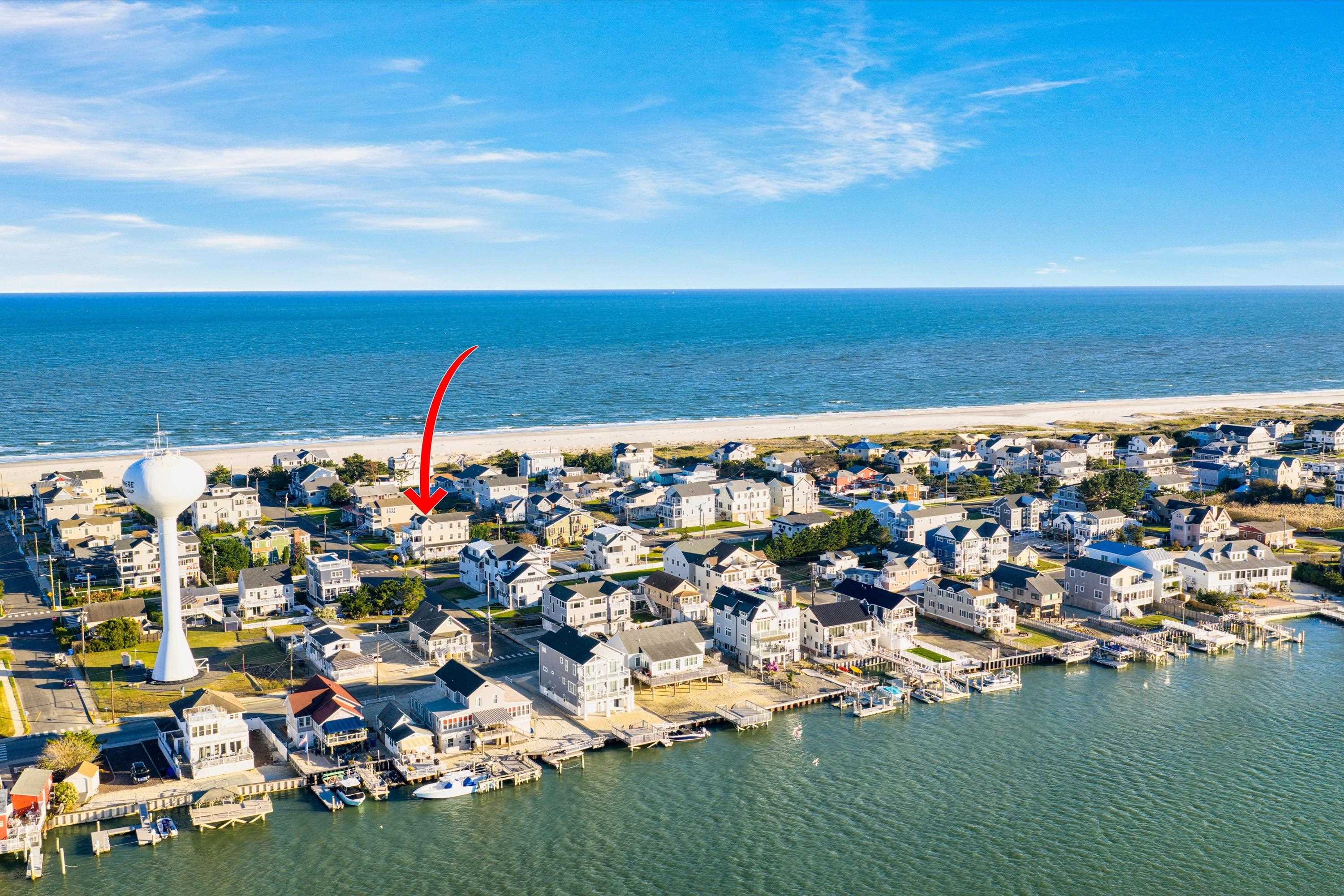 Aerial view of the marked coastal home between the ocean beach and waterfront neighborhood.