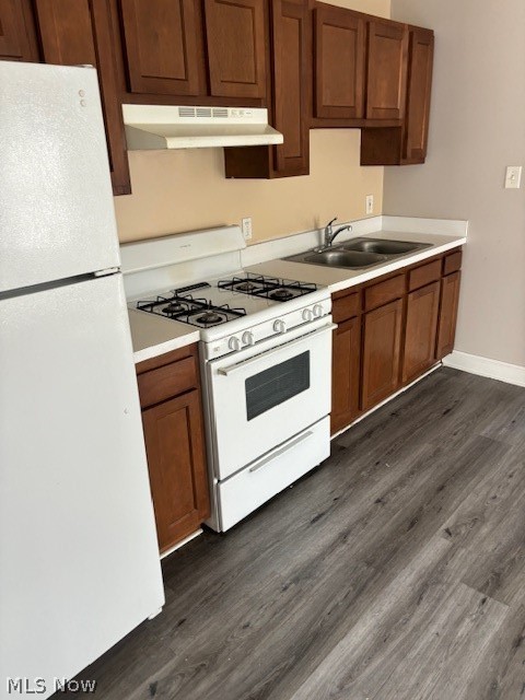 Kitchen with dark wood cabinets, a white gas range, and a double-basin sink.
