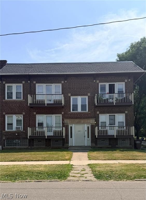 Two-story brick apartment building with several balconies and a central entrance.