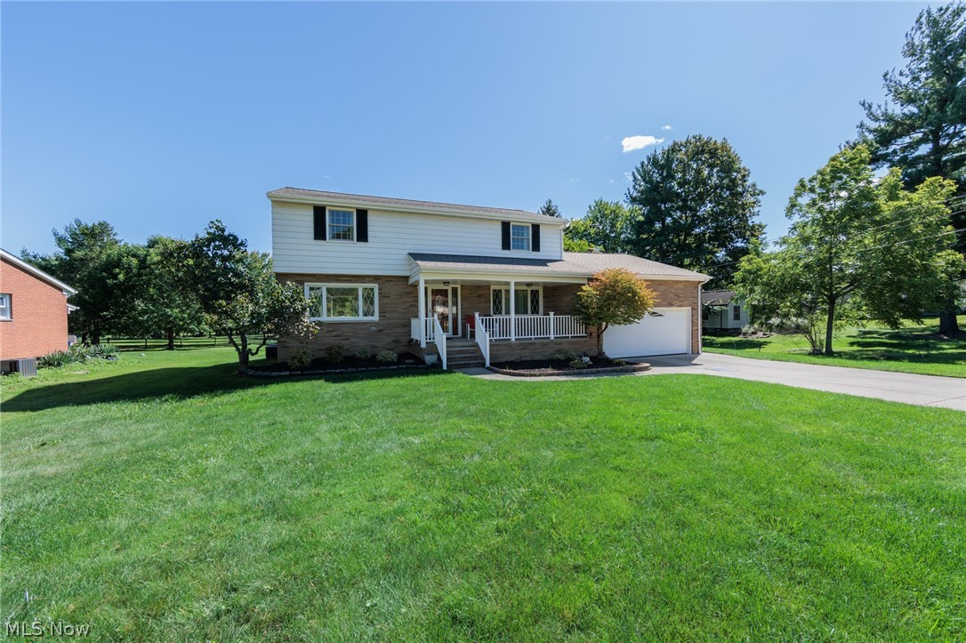 Two-story home with a covered porch, attached garage, and broad green lawn.