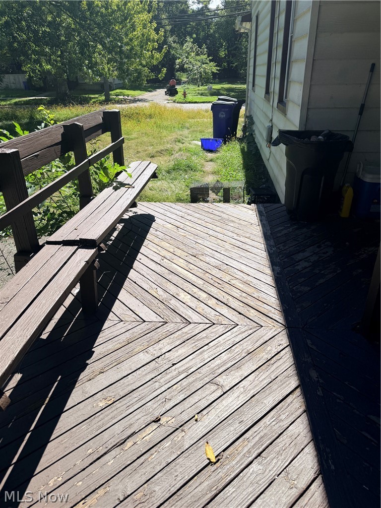 Wooden deck with a built-in bench overlooking a grassy, tree-lined yard.