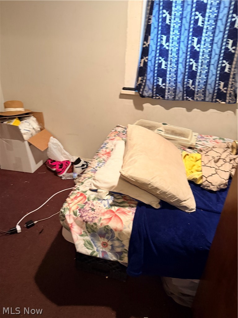 Bedroom with floral bedding, a dark blue blanket, and a patterned curtain.