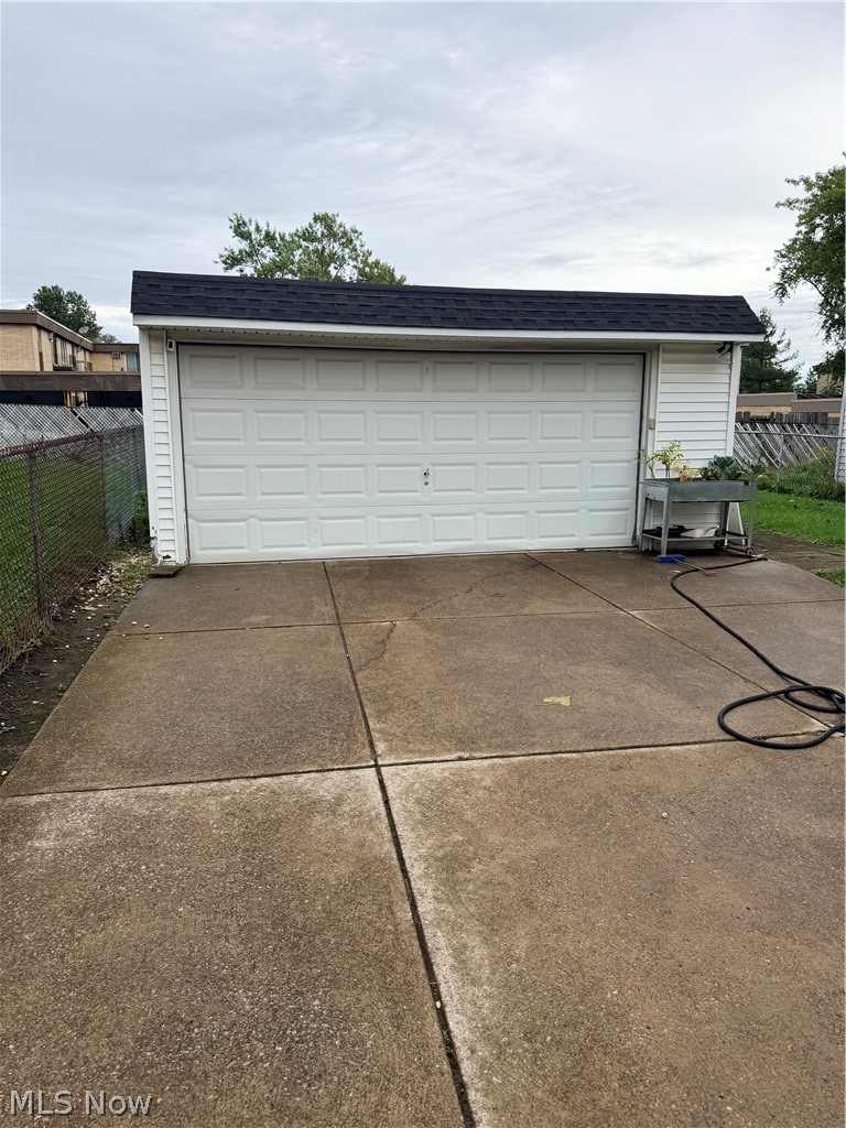 Detached white two-car garage with a dark roof and wide concrete driveway.