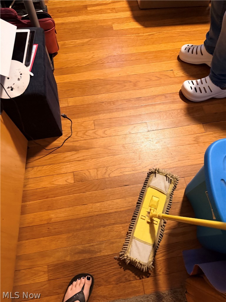 Hardwood flooring with a mop and personal belongings around the edges.