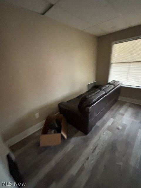 Living room with a dark leather sofa, gray flooring, and a window with blinds.