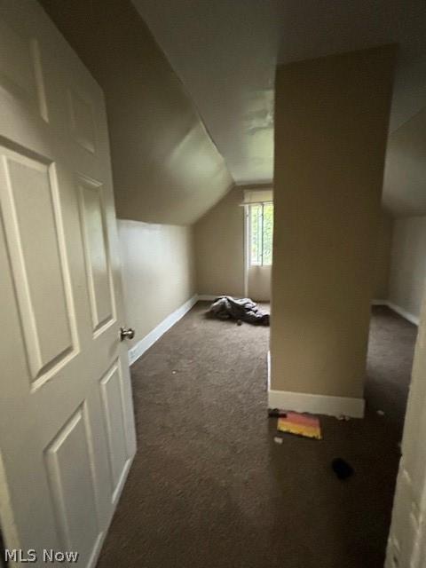 Carpeted attic bedroom with a central partition, sloped ceiling, and small window.