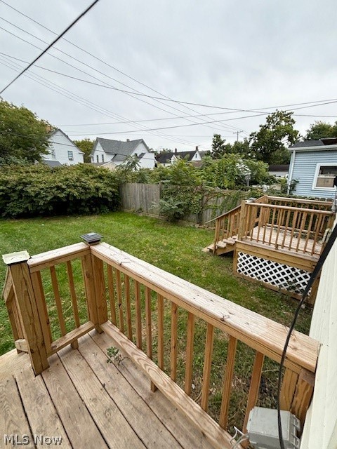 Backyard with two raised wooden decks, a fenced lawn, and mature shrubs.