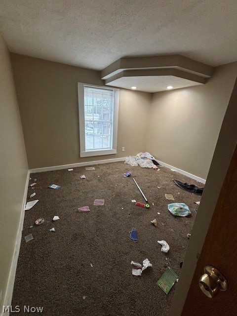 Carpeted room with a single window, recessed tray ceiling, and scattered debris.