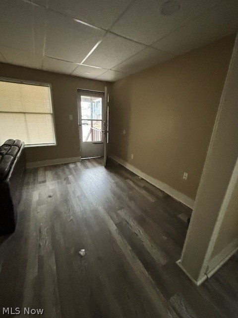 Living room with dark wood-look flooring, a window, and a glass door.